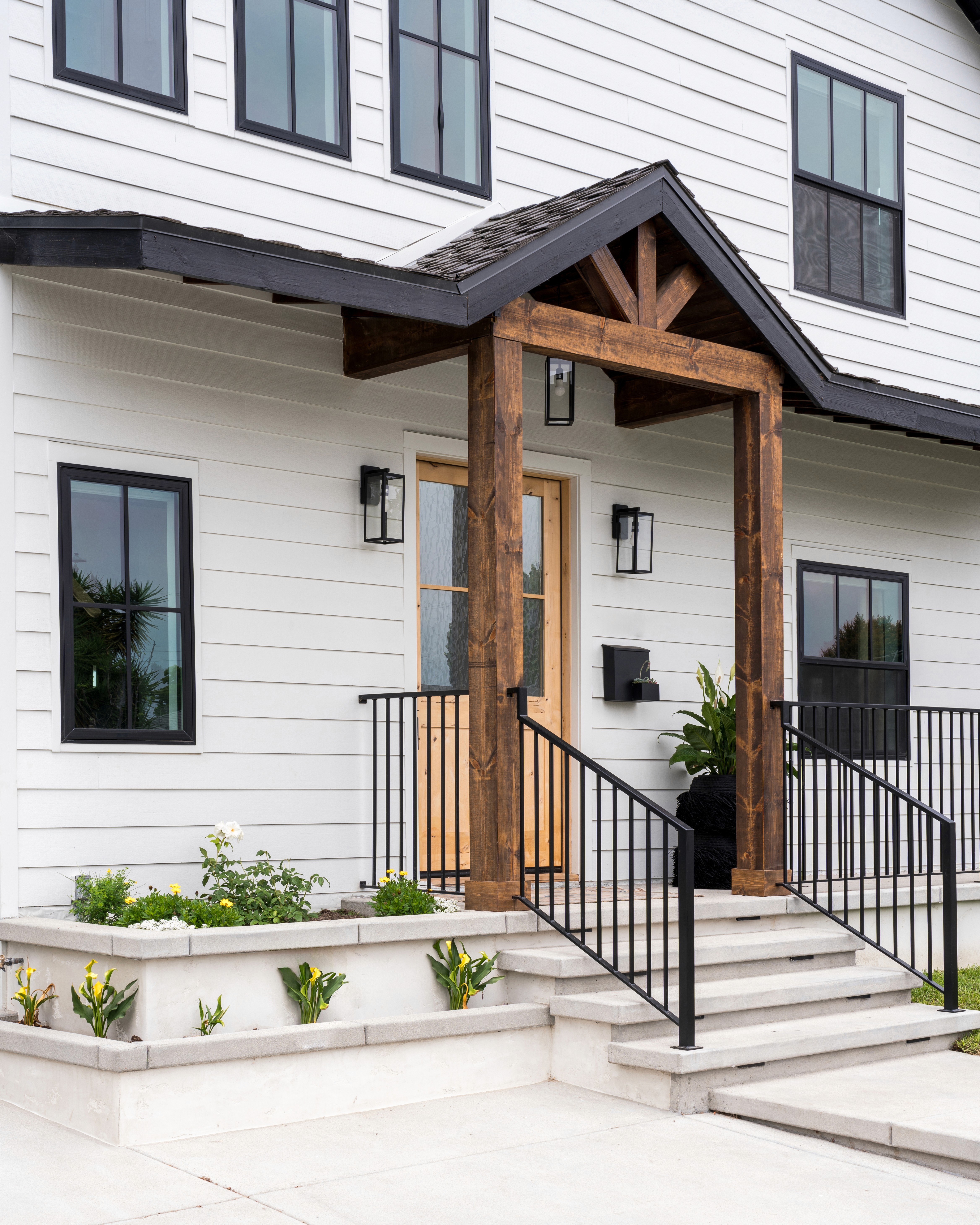 A two-story home with white siding and warm wood accents by Jubilee Interiors located in Westlake Village, CA
