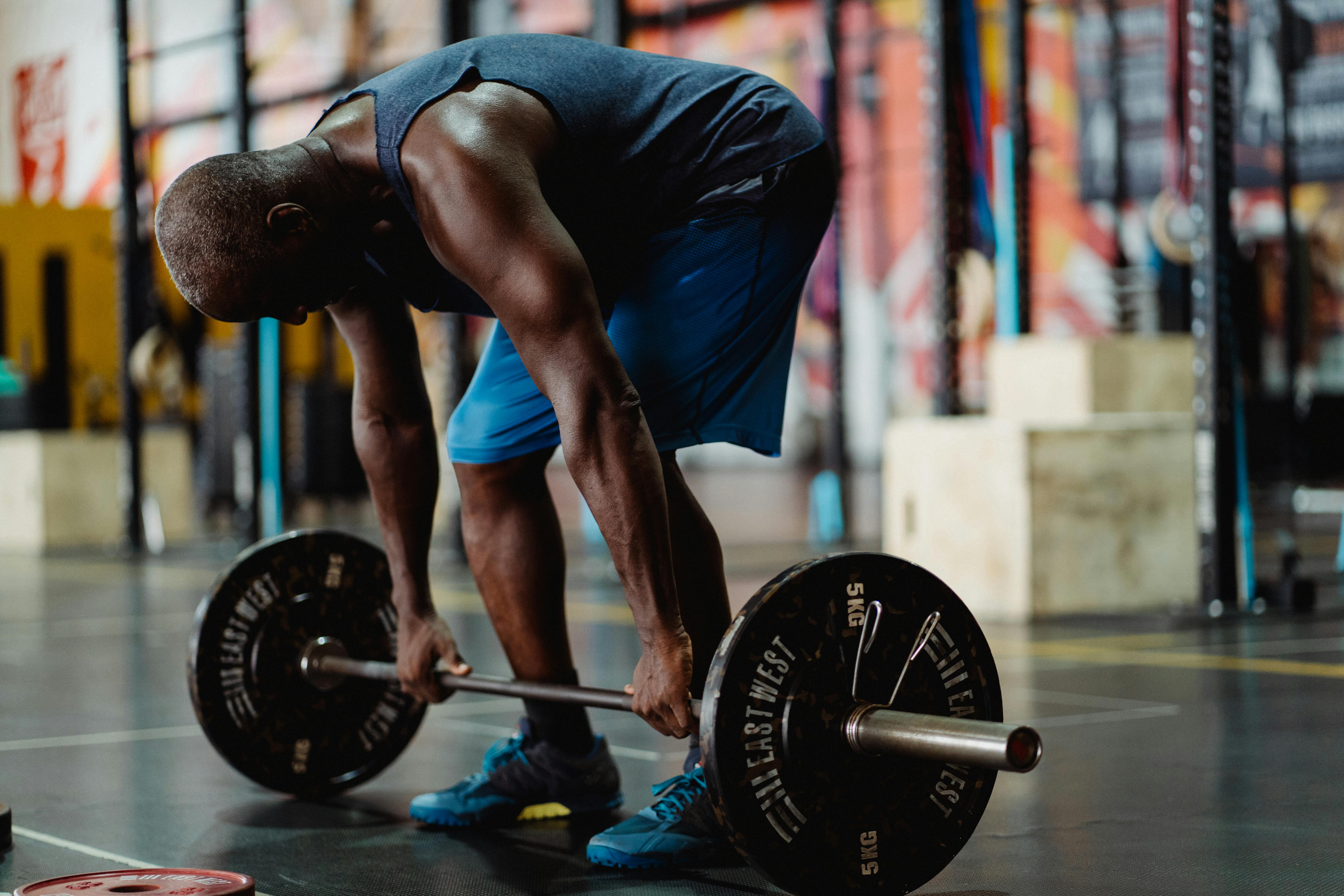 Man lifts weights in a gym environment.