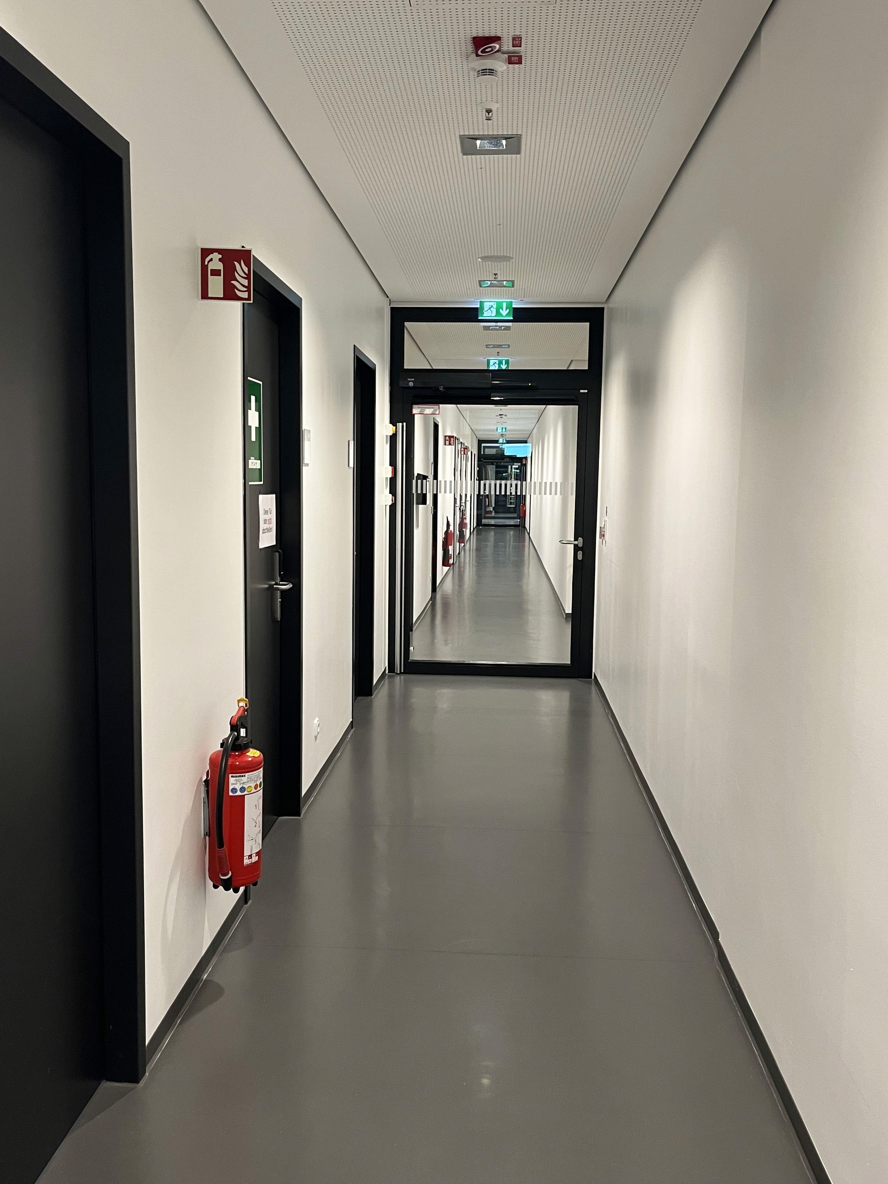 Flur mit Glastrenntür weißen Wänden und schwarzen Türen