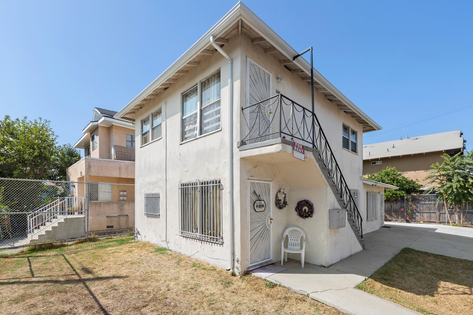 A two-story residential building at 4421 Wall, with a stairway and several windows, set against a clear blue sky.