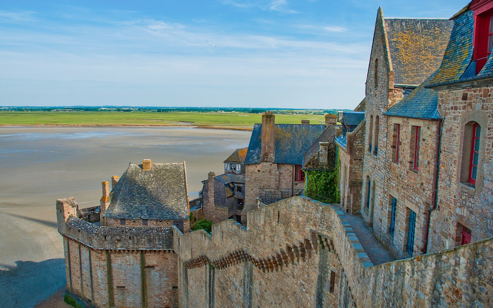 Mont St. Michel stone buildings and walls with tidal flats in the background.
