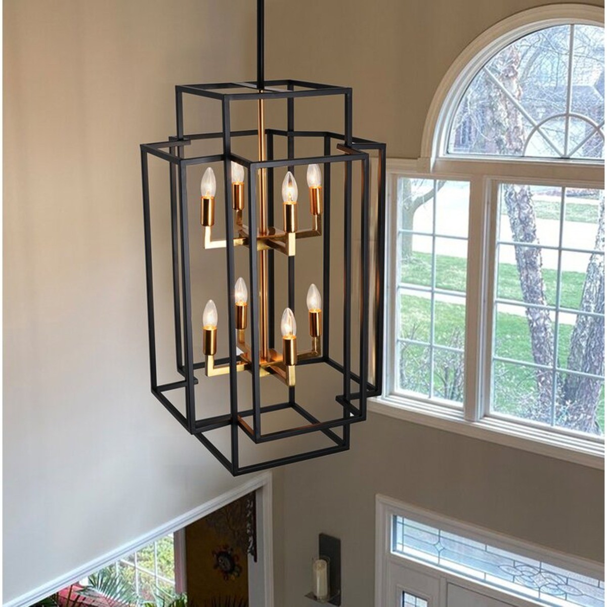 Black rectangle chandelier with candle stick lightbulbs hanging in an entryway.