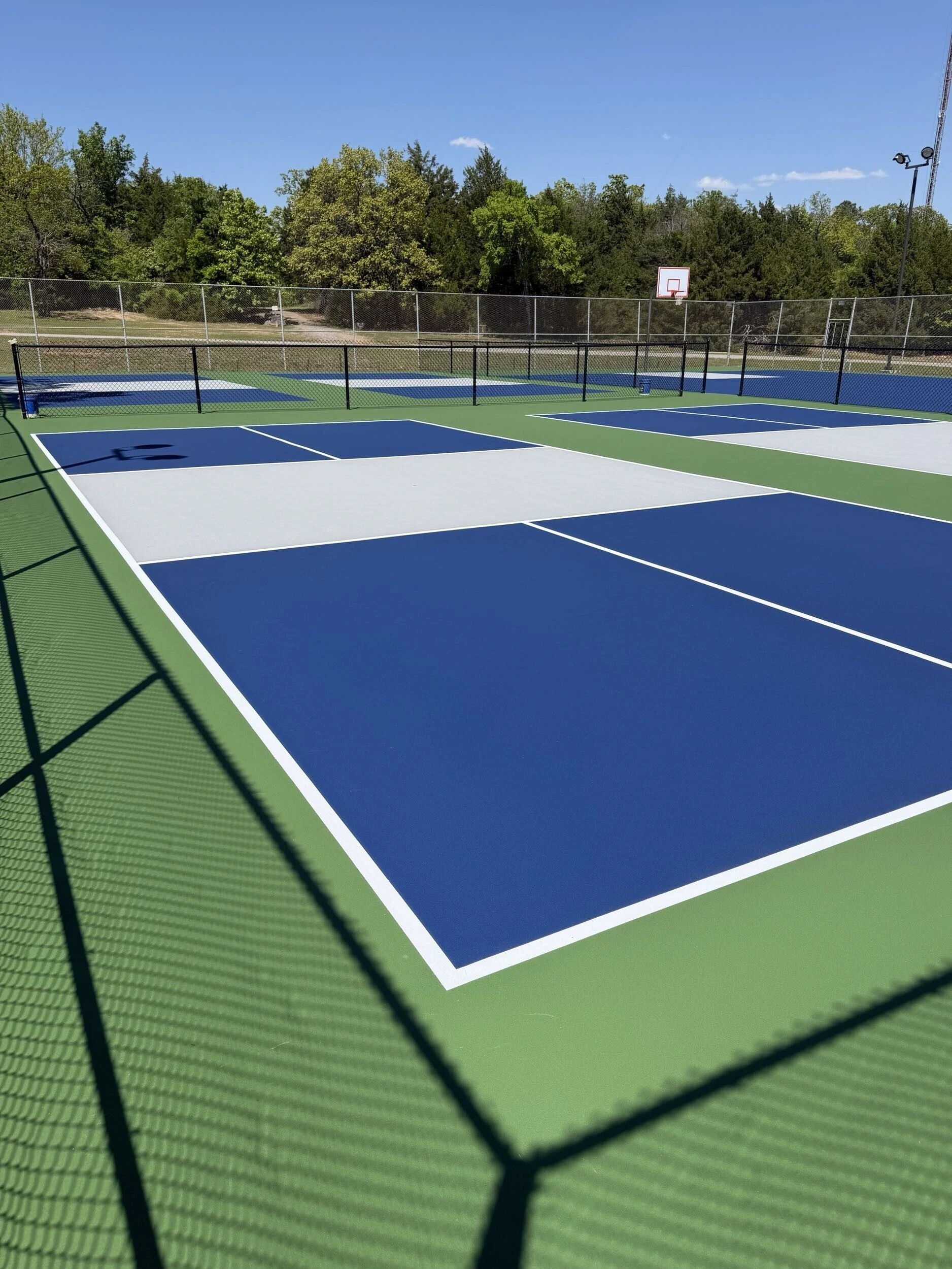 Newly resurfaced pickleball courts with green out-of-bounds and gray kitchen zones at Bell Park in Greenwood, AR