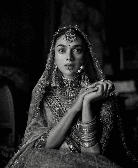 Dramatic black and white portrait of a bride adorned in traditional Indian jewelry, exuding elegance and grace. A classic example of fine art wedding photography with a focus on timeless cultural beauty.