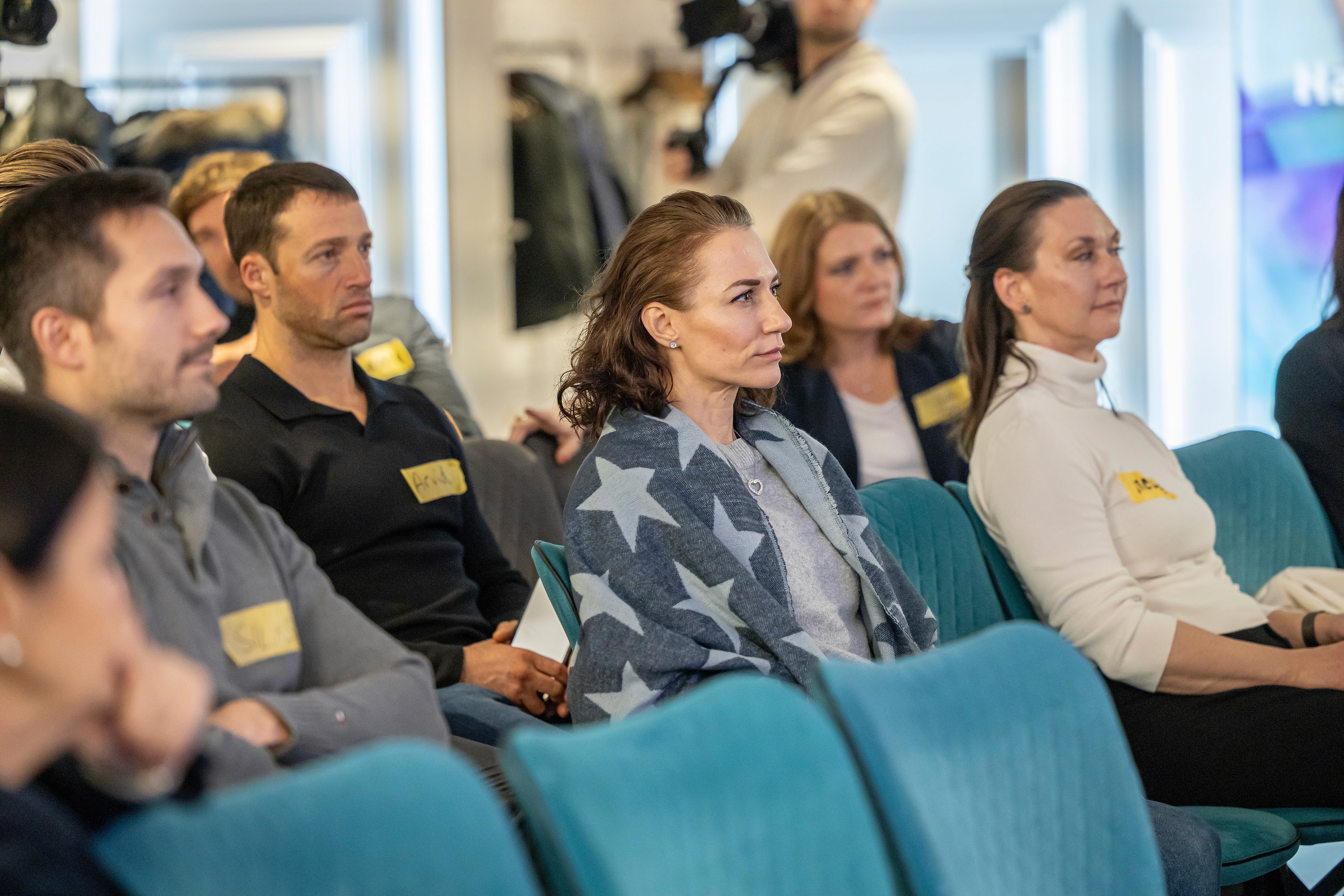 People crossing a busy street with cars and buildings.