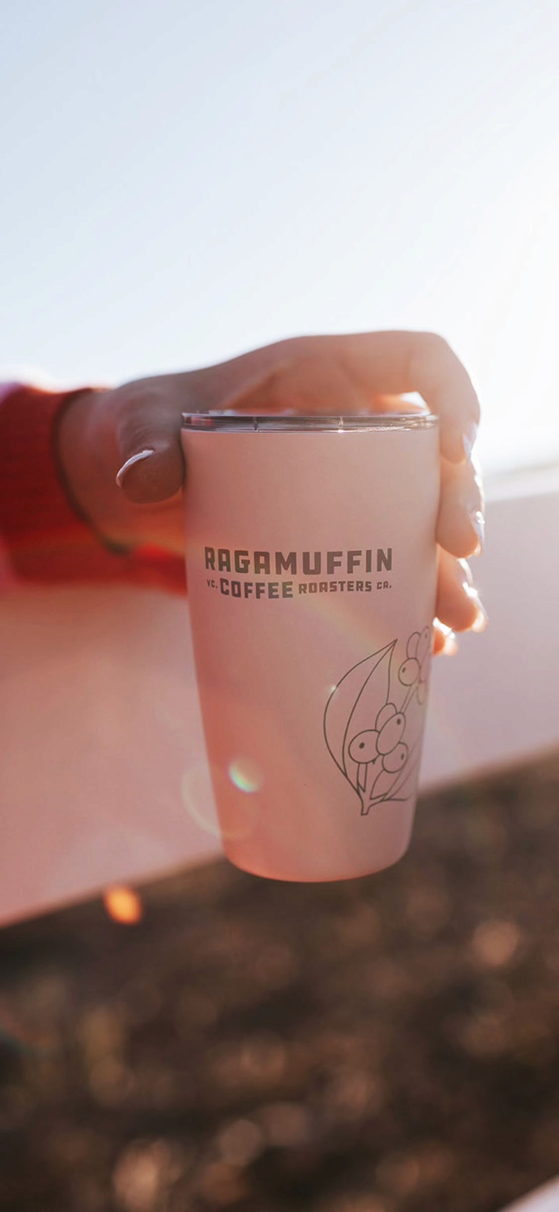 Ragamuffin branded coffee cup in soft pink lighting