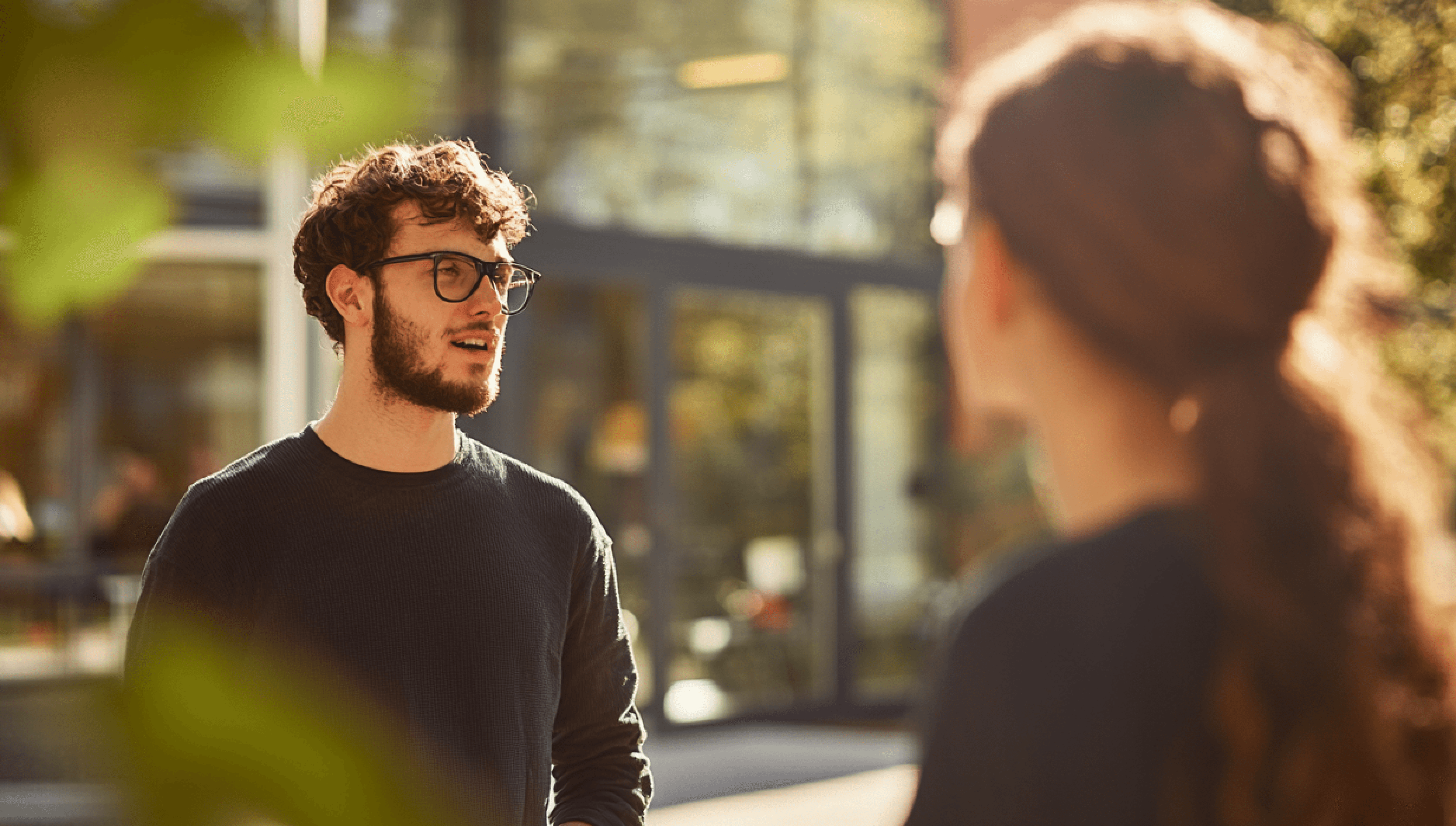 Image of two people standing outdoors, engaged in conversation.