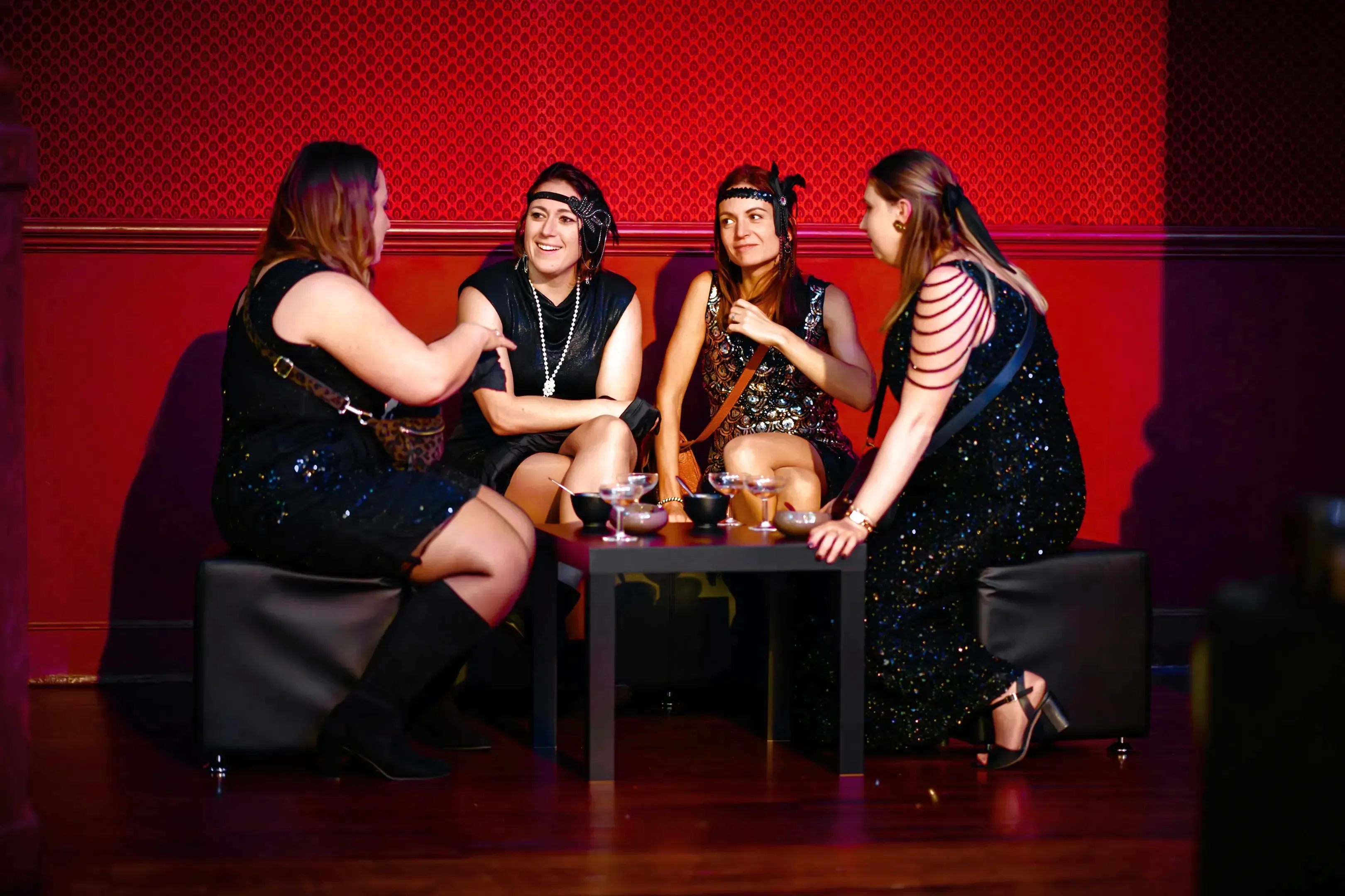 Groupe de participantes en tenue années 30 discutant autour d’une table pendant une soirée événementielle