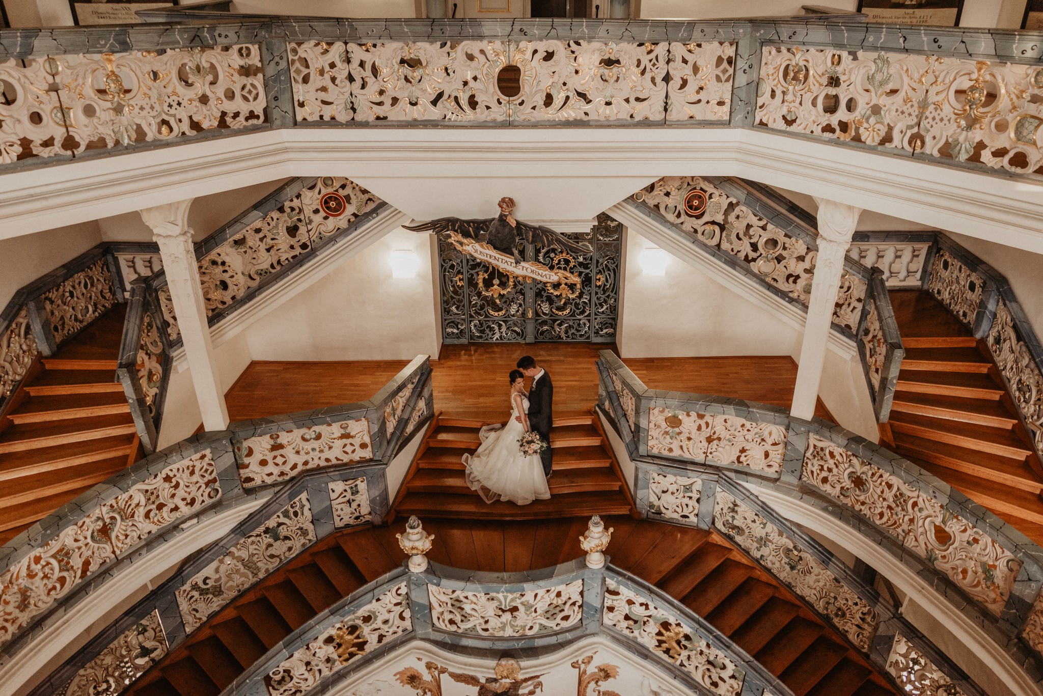 Ein Brautpaar küsst sich auf einer prunkvollen, historischen Treppe – exklusiver Service und hochwertige Hochzeitsfotografie von Nicole Grasmann.