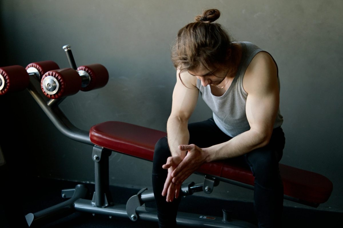 A man sits on a piece of strength-training equipment.