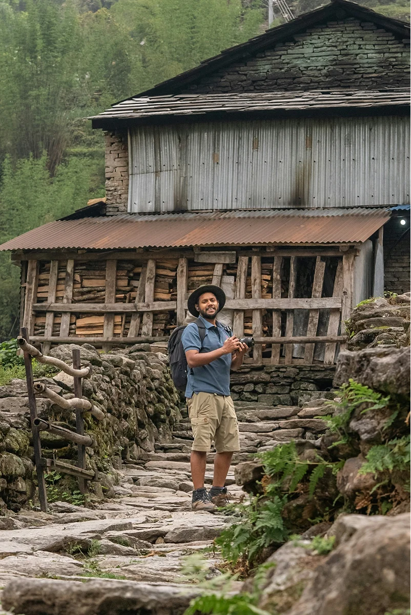 Person standing beside a weathered wooden house