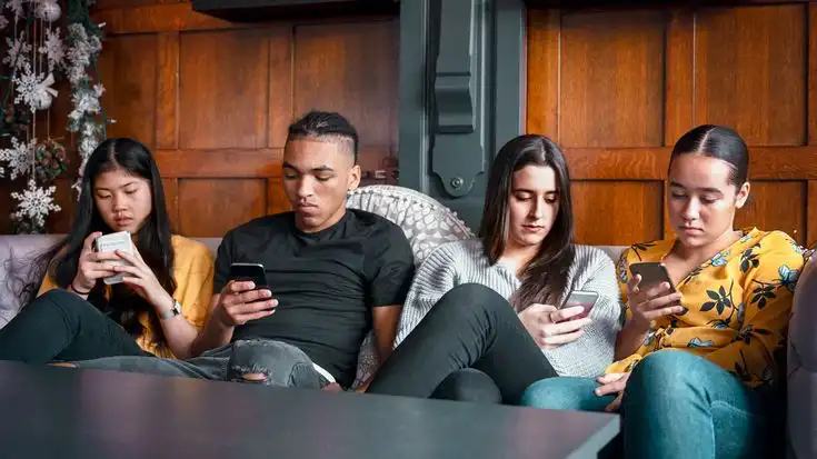 A group of younfg people starring and looking addicted to their phones