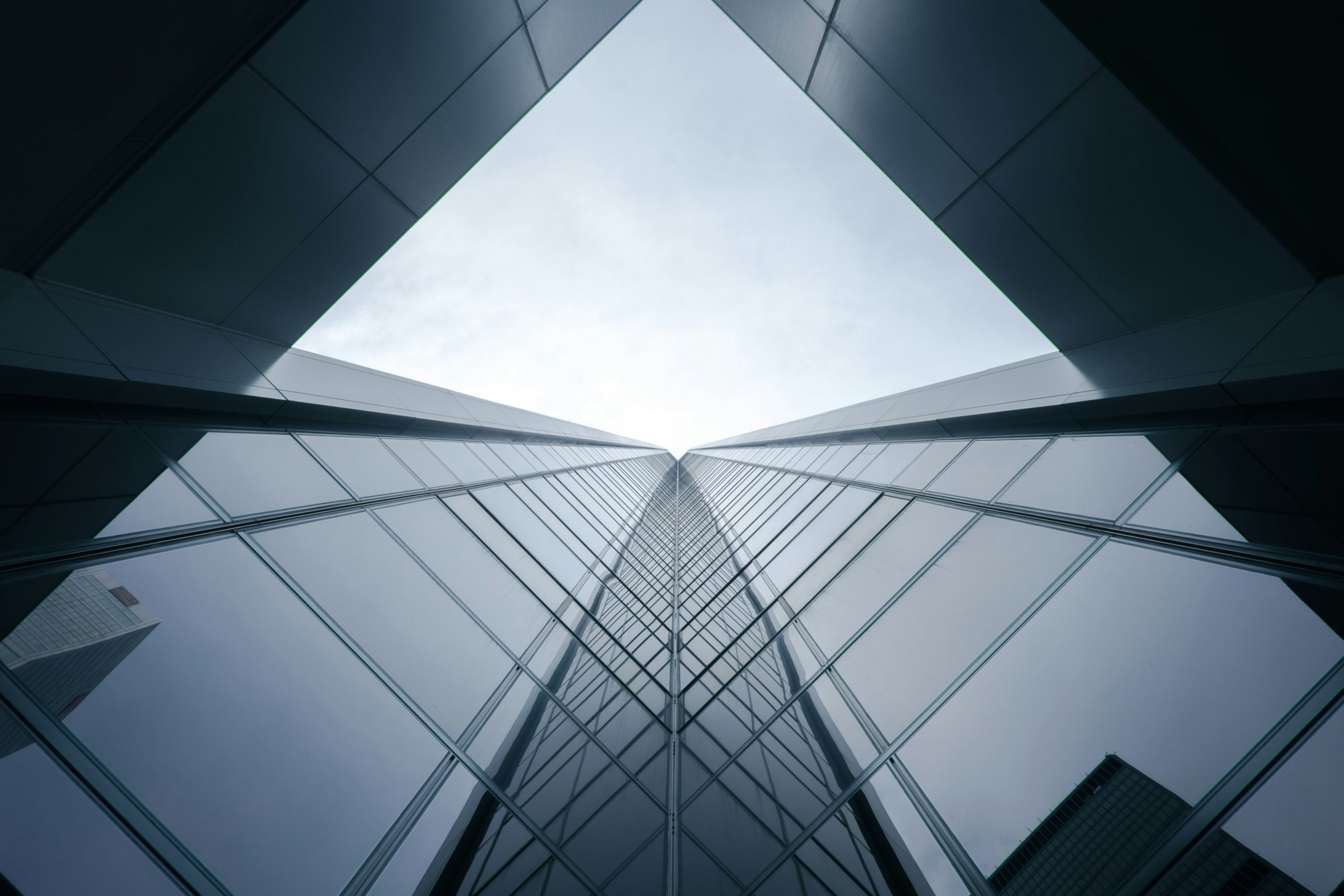 A low-angle view of tall skyscrapers converging towards a bright sky at the top, creating a sense of depth.