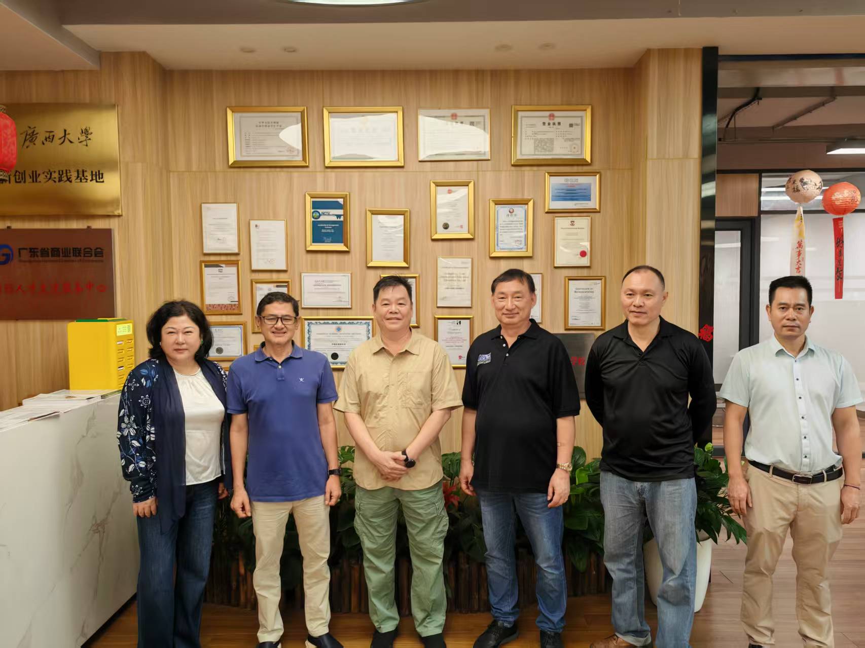 HYEDU and Siyao School representatives pose for a group photo in front of the school's credentials wall