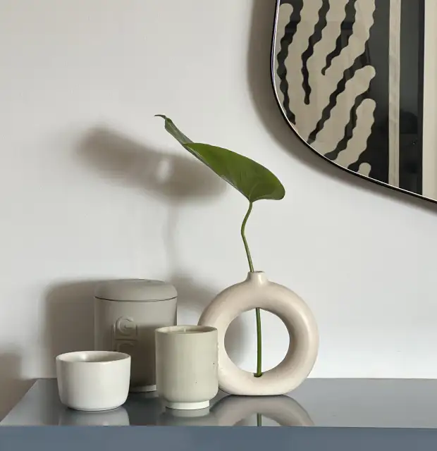 Composición minimalista con cerámicas neutras y hoja verde para marcas de interiorismo que comunican equilibrio, calma y diseño contemporáneo.