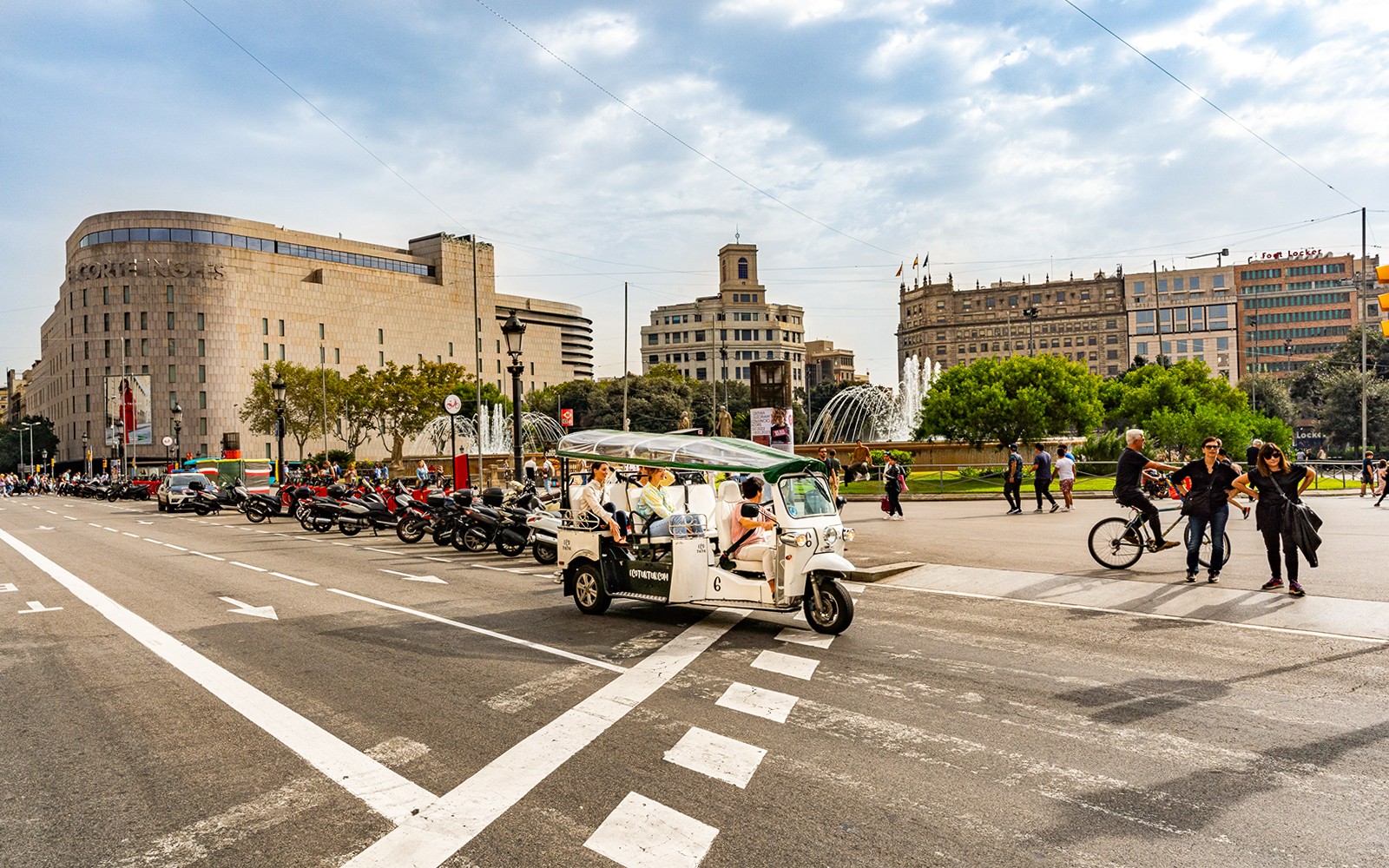Tuk tuk driving through Barcelona streets with Sagrada Familia in the background.