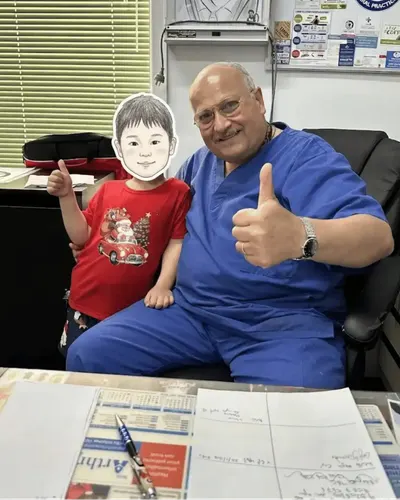 Dr. Saddik sharing a positive moment with a young child patient in his private consultation room.