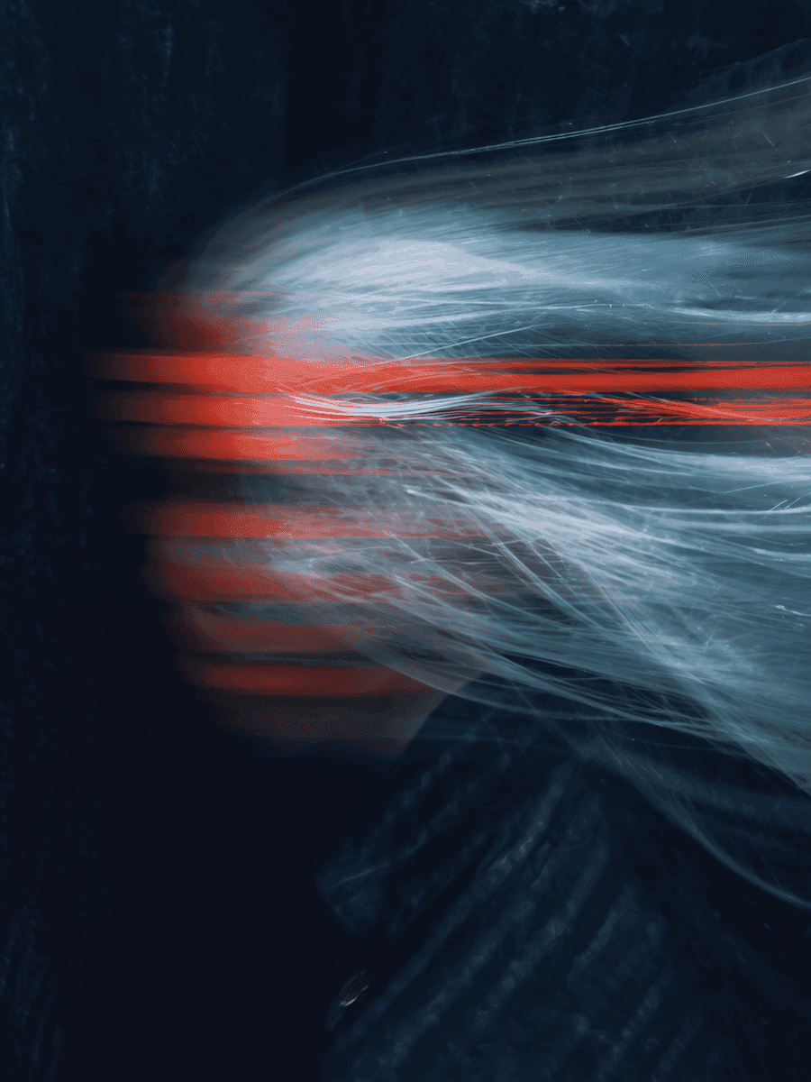 Abstract motion blur of white hair with red streaks on a dark background, creating a dynamic and artistic visual effect.