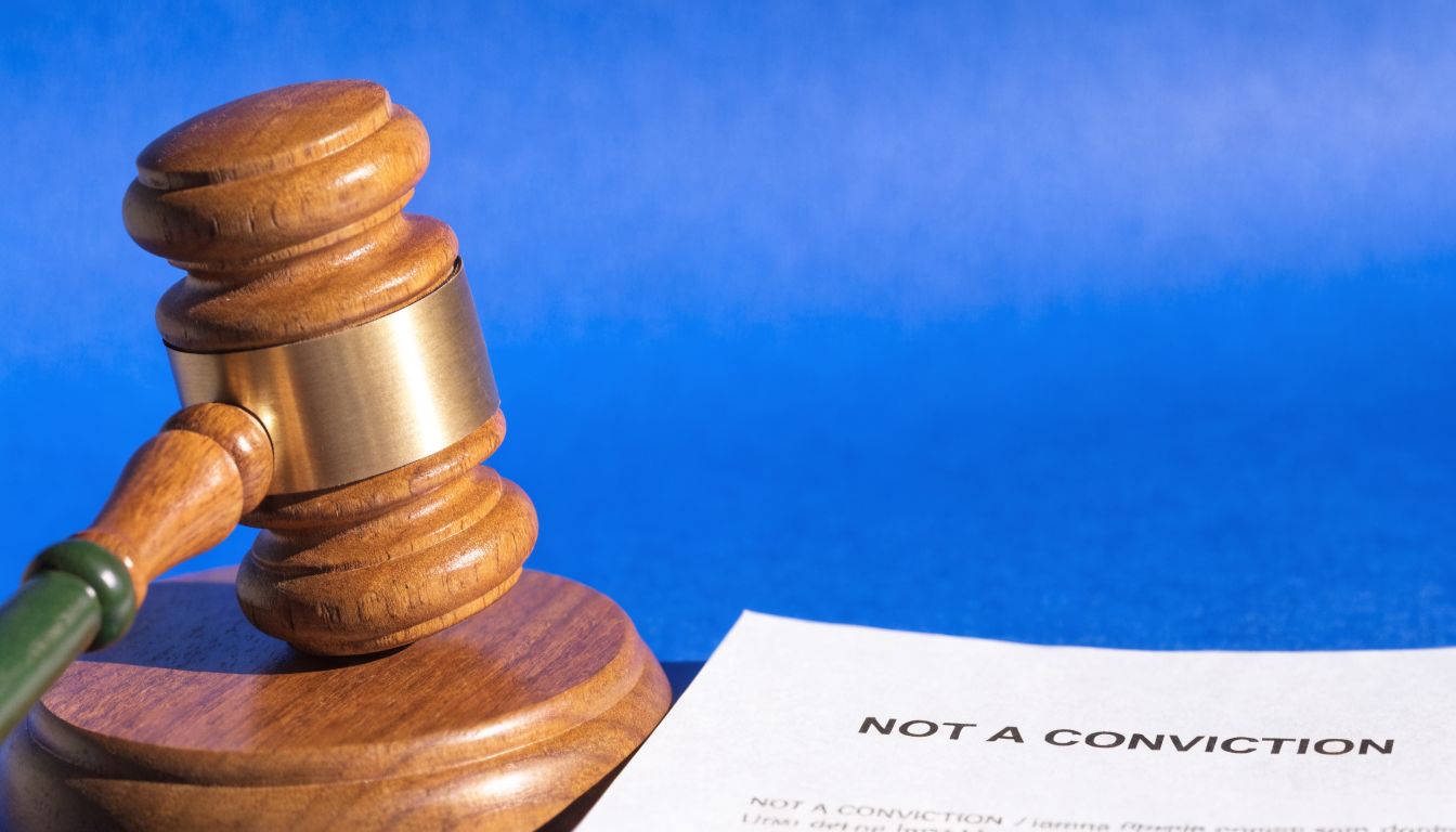 A wooden judge gavel resting next to a document labeled not a conviction on a blue background.
