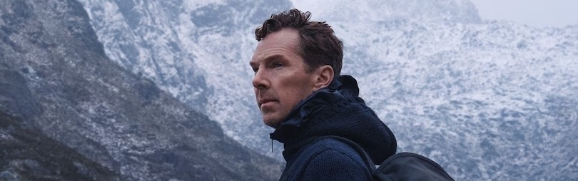Man dressed in dark casual wear sitting alone in a stadium’s empty rows of purple chairs, lit by dramatic moody lighting.