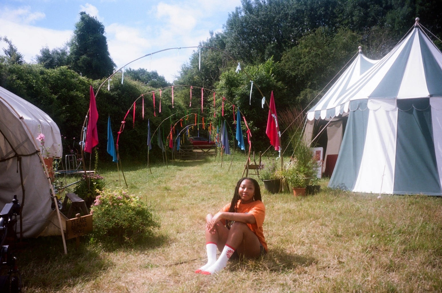 A woman sits on the grass surrounded by tents and festival decorations