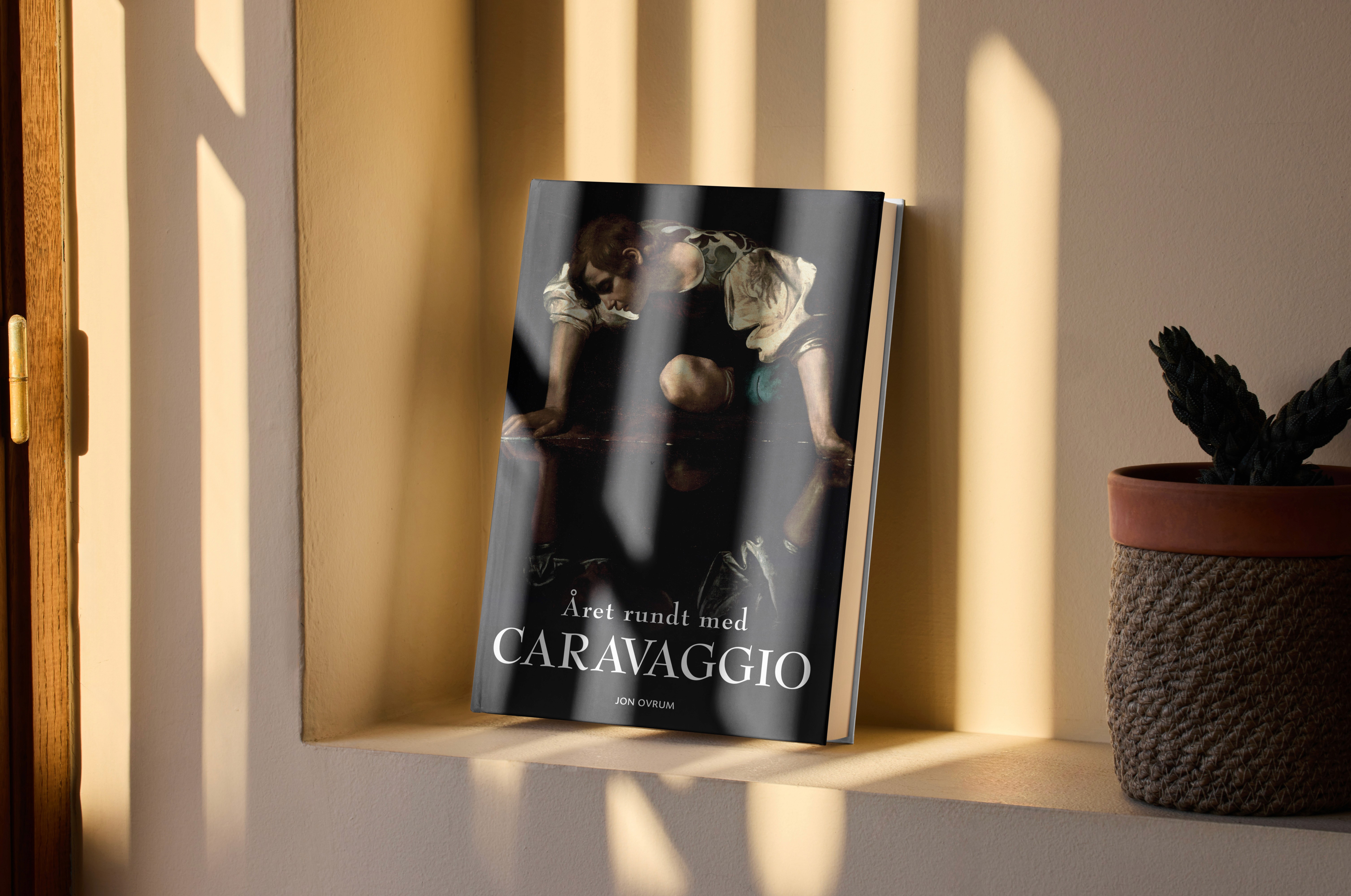 Książka Året rundt med Caravaggio oparta o ścianę w ciepłym świetle.