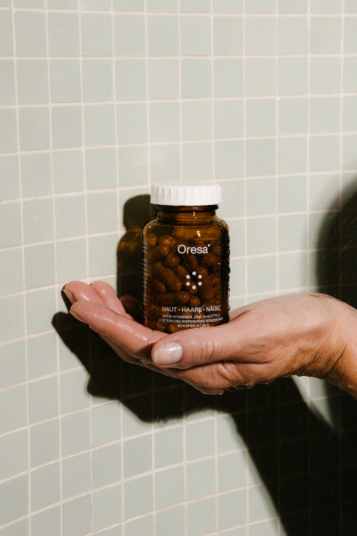 Hand hält Oresa Haut Haare Nägel Kapseln in Glasflasche
