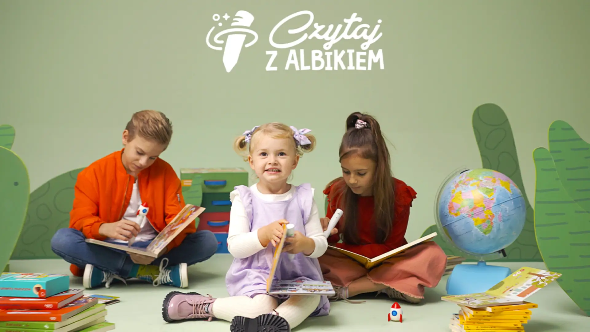 Trójka dzieci siedzących z książkami na planie kampanii Czytaj z Albikiem