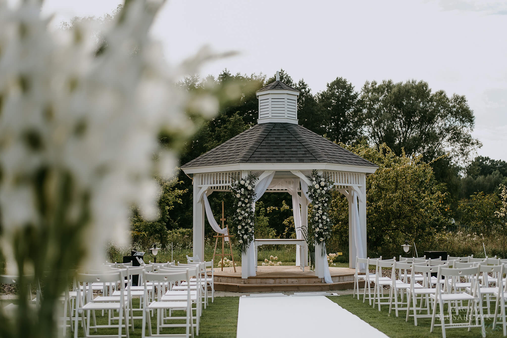 Elevated view of an outdoor wedding ceremony setup in a forest clearing with wooden chairs