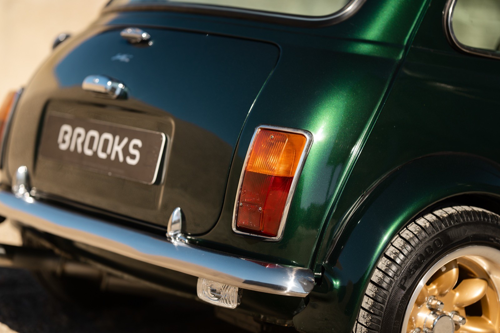 A small, green and black vehicle parked on a sandy surface, with a warm sunset lighting the scene.
