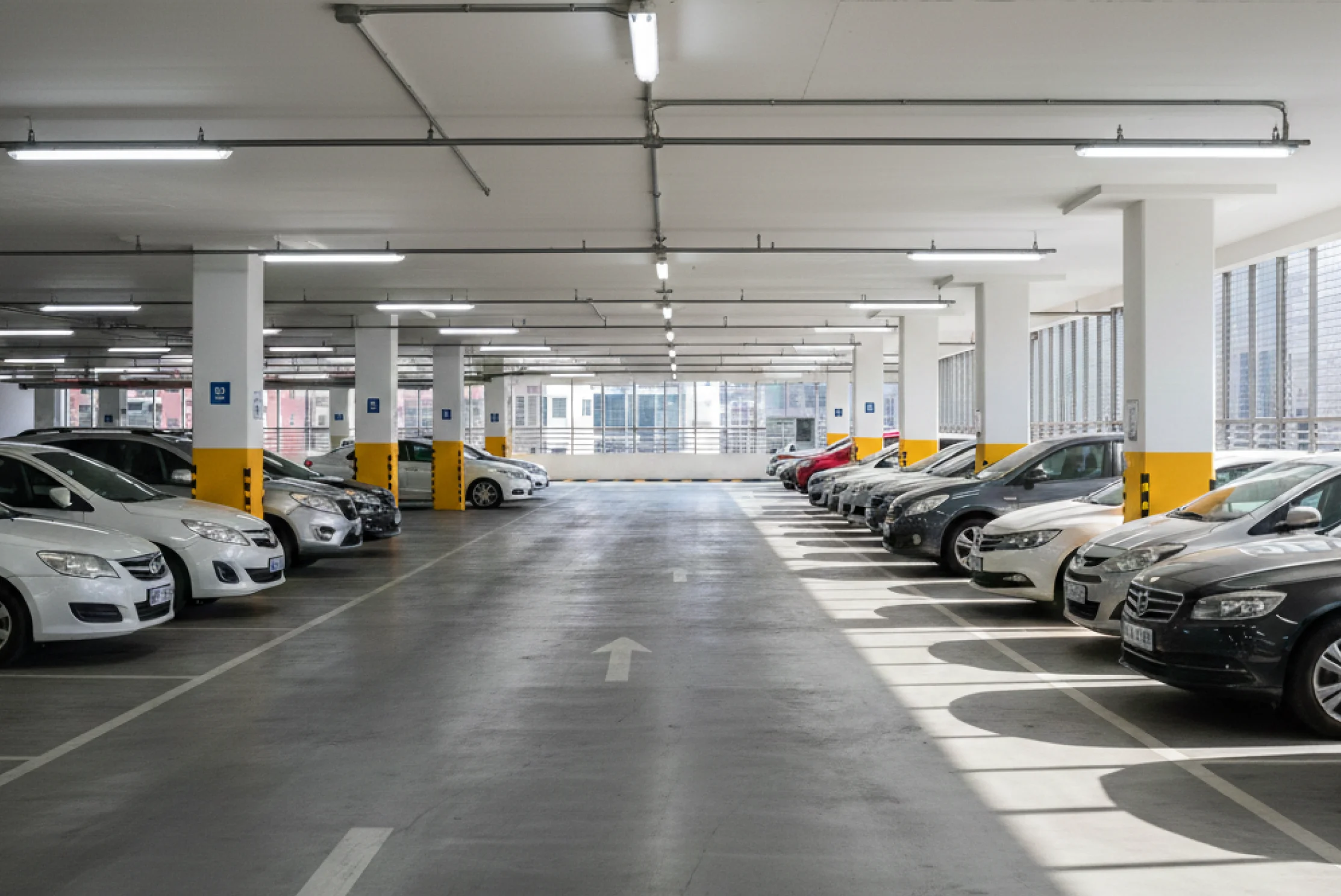 차량이 양쪽으로 주차된 밝은 실내 주차장 통로 전경