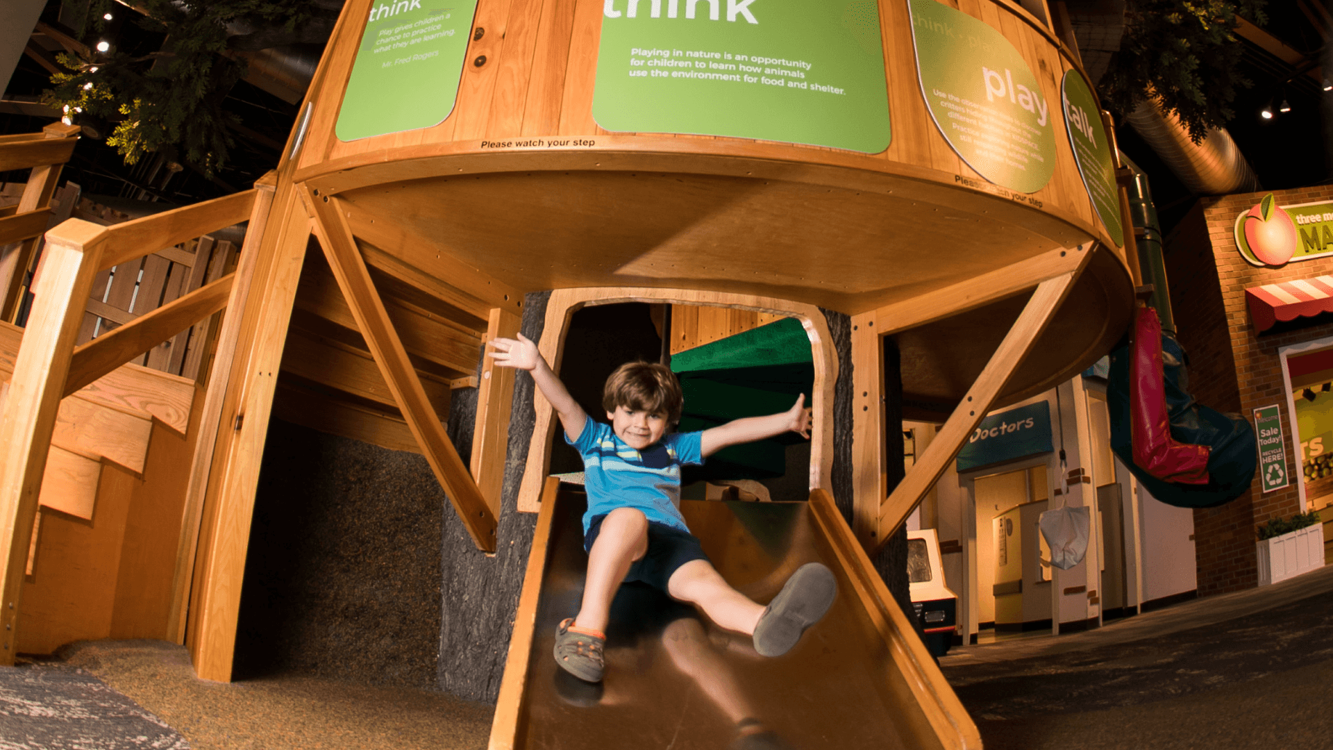 A young boy slides down the ramp at the Tree House.