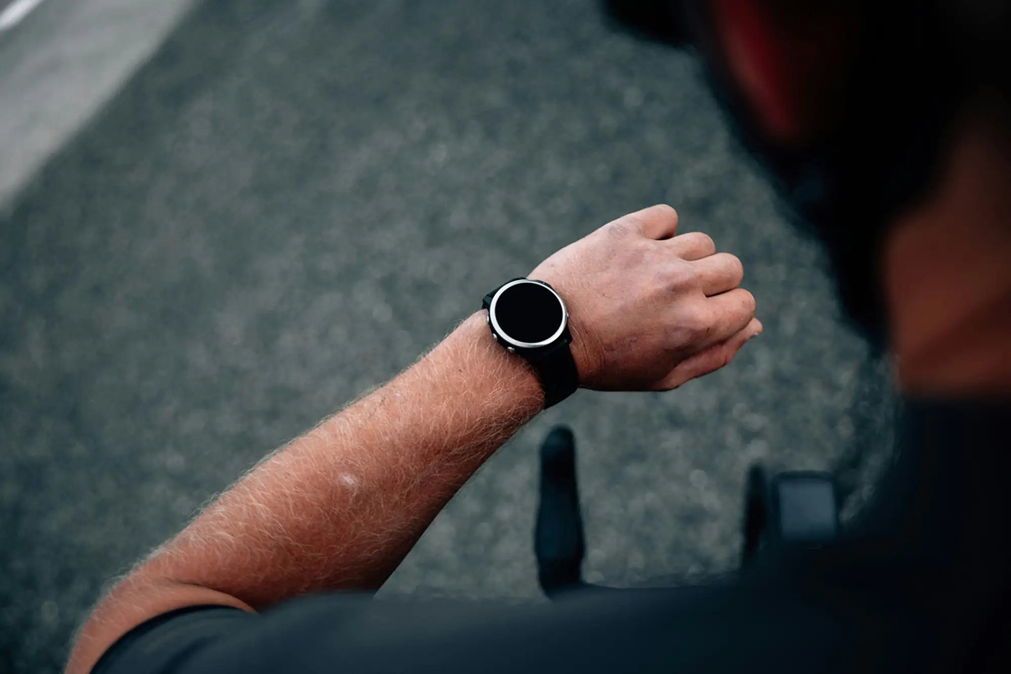 Close-up of a triathlete monitoring their pace and performance data on a GPS watch during an Ironman training session