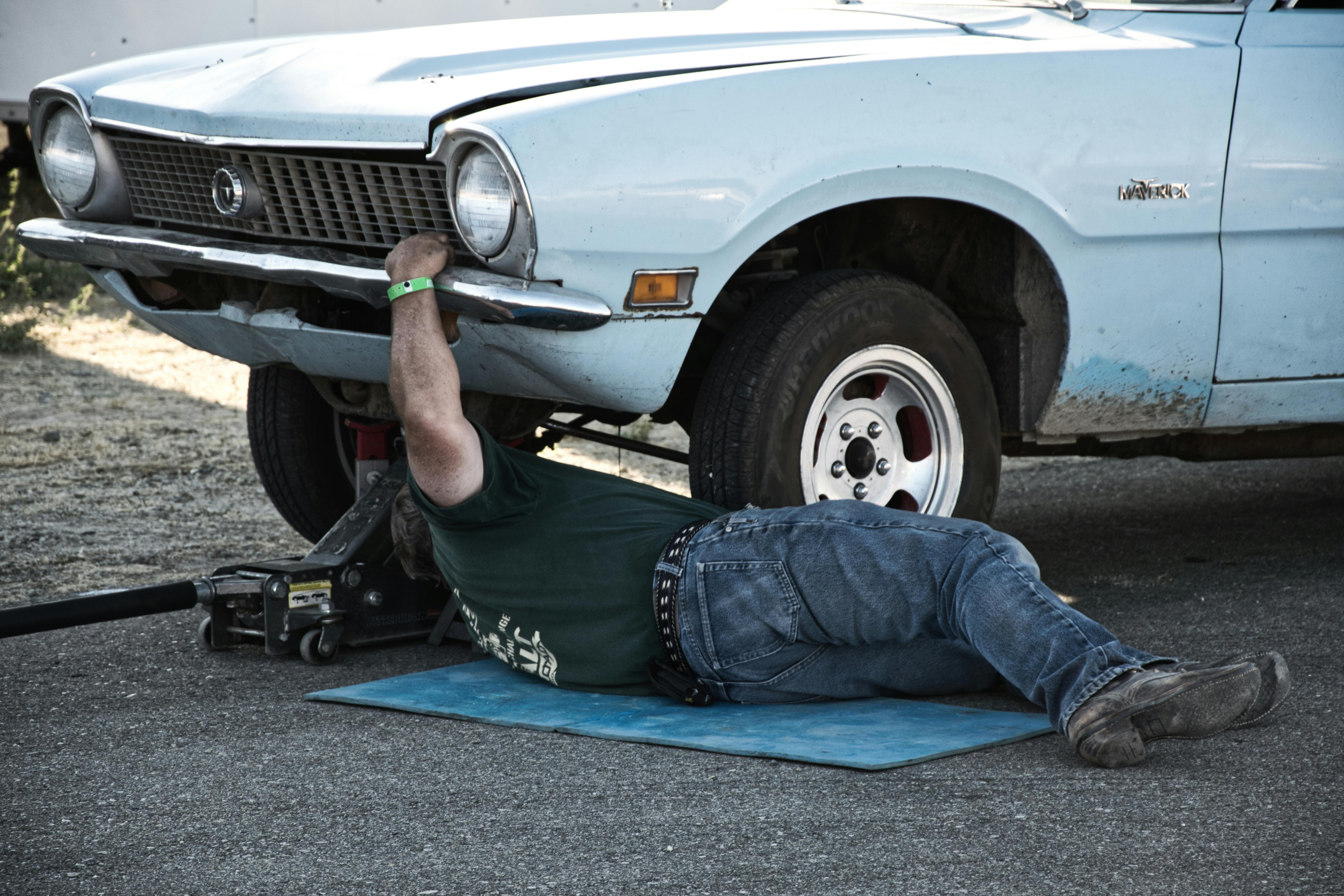 Mechanic working underneath an old car