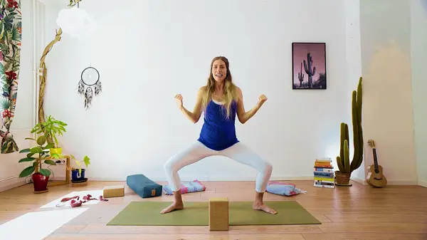 Pregnant woman in a standing yoga pose with props – prenatal yoga class to open the chest and shoulders while maintaining core integrity during pregnancy