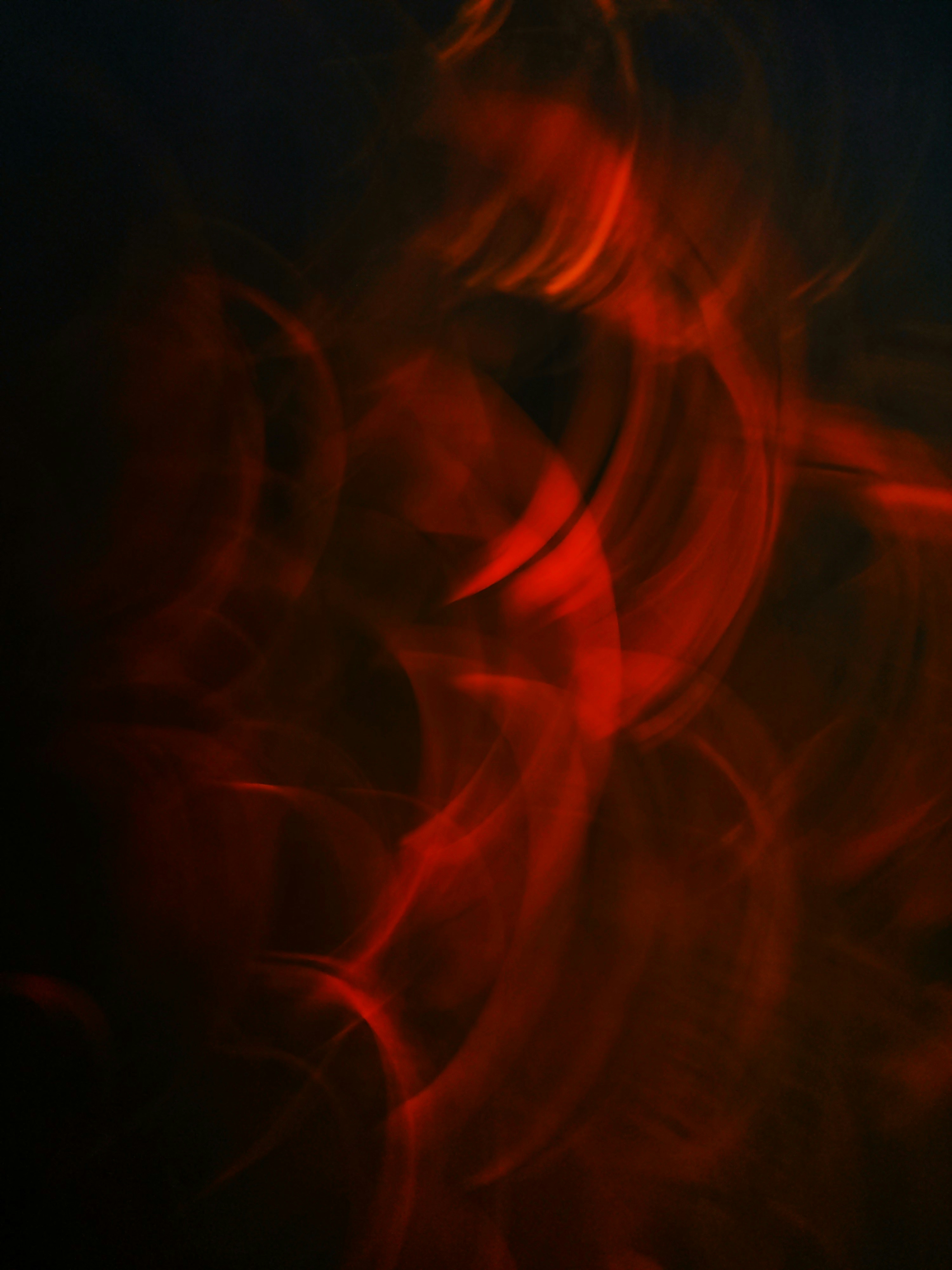 Abstract swirls of red light against dark background