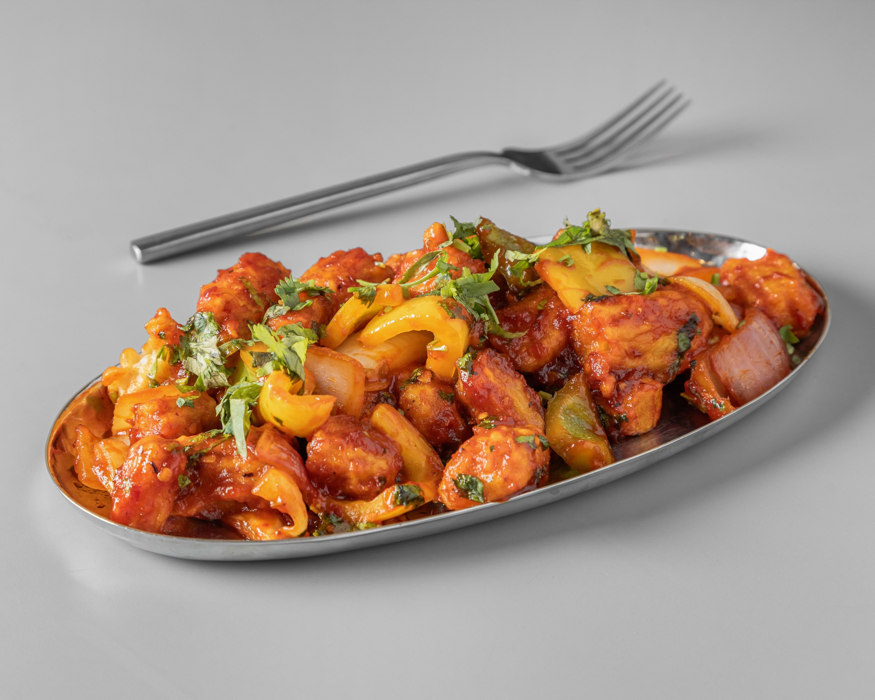 A stack of glazed, braised pork belly cubes (possibly Chinese Red Braised Pork or Japanese Kakuni), drizzled with a dark sauce and topped with shredded green onions and orange zest, served on a vintage metal plate.