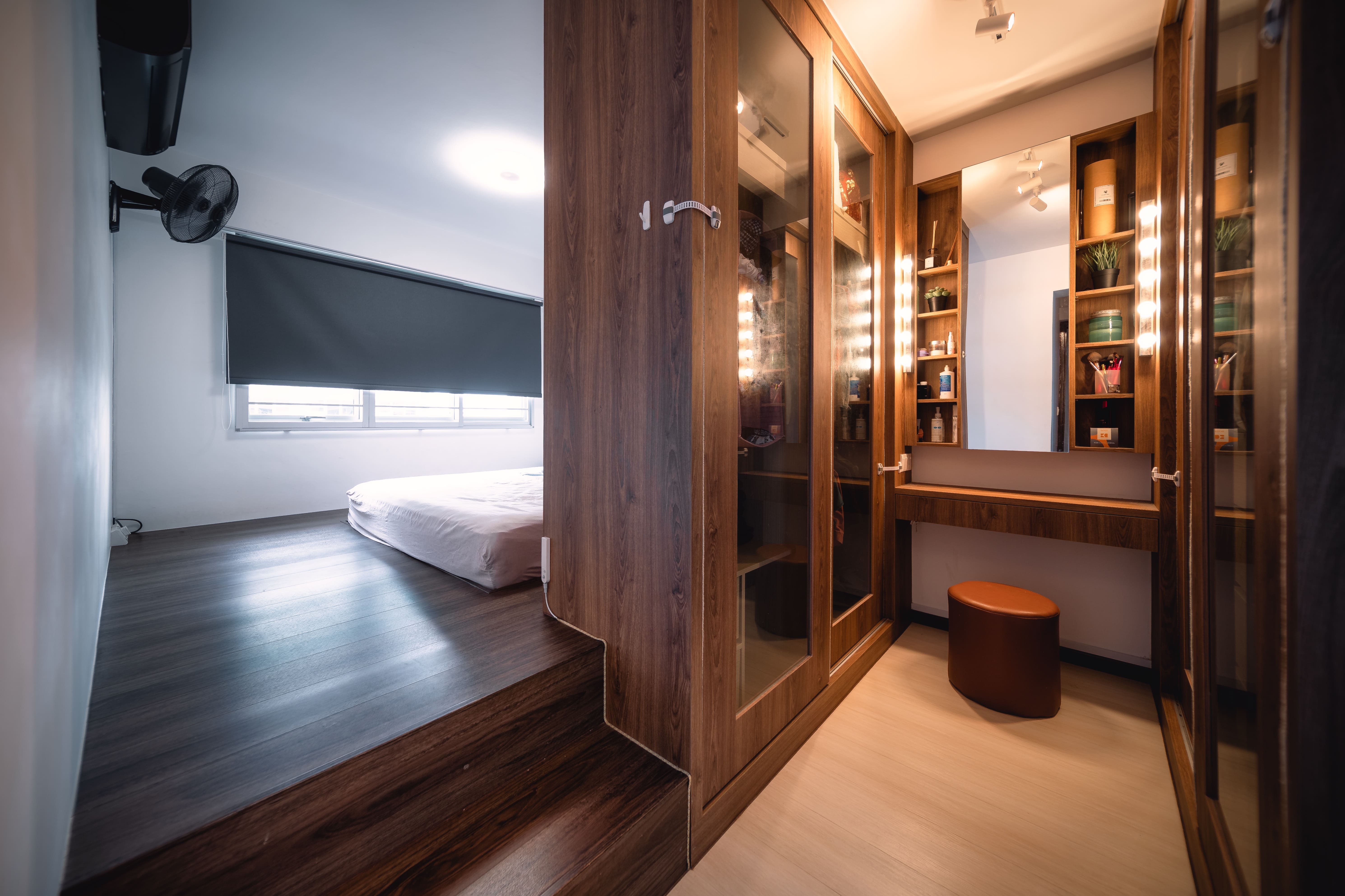 Raised master bedroom with adjoining walk-in wardrobe and vanity, styled with a mix of dark and light wood finishes.