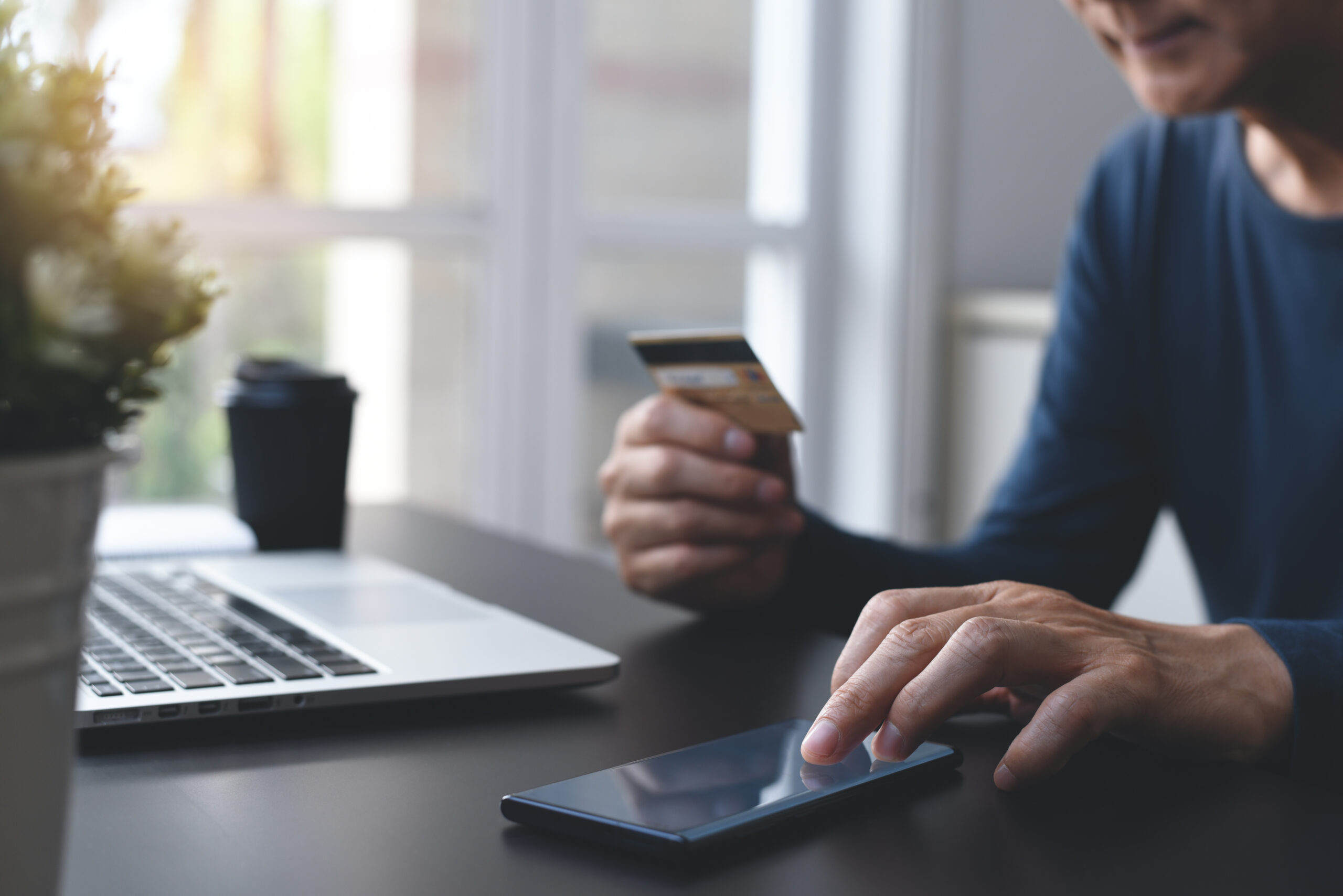 Man using mobile phone and credit card in the process of e-shopping
