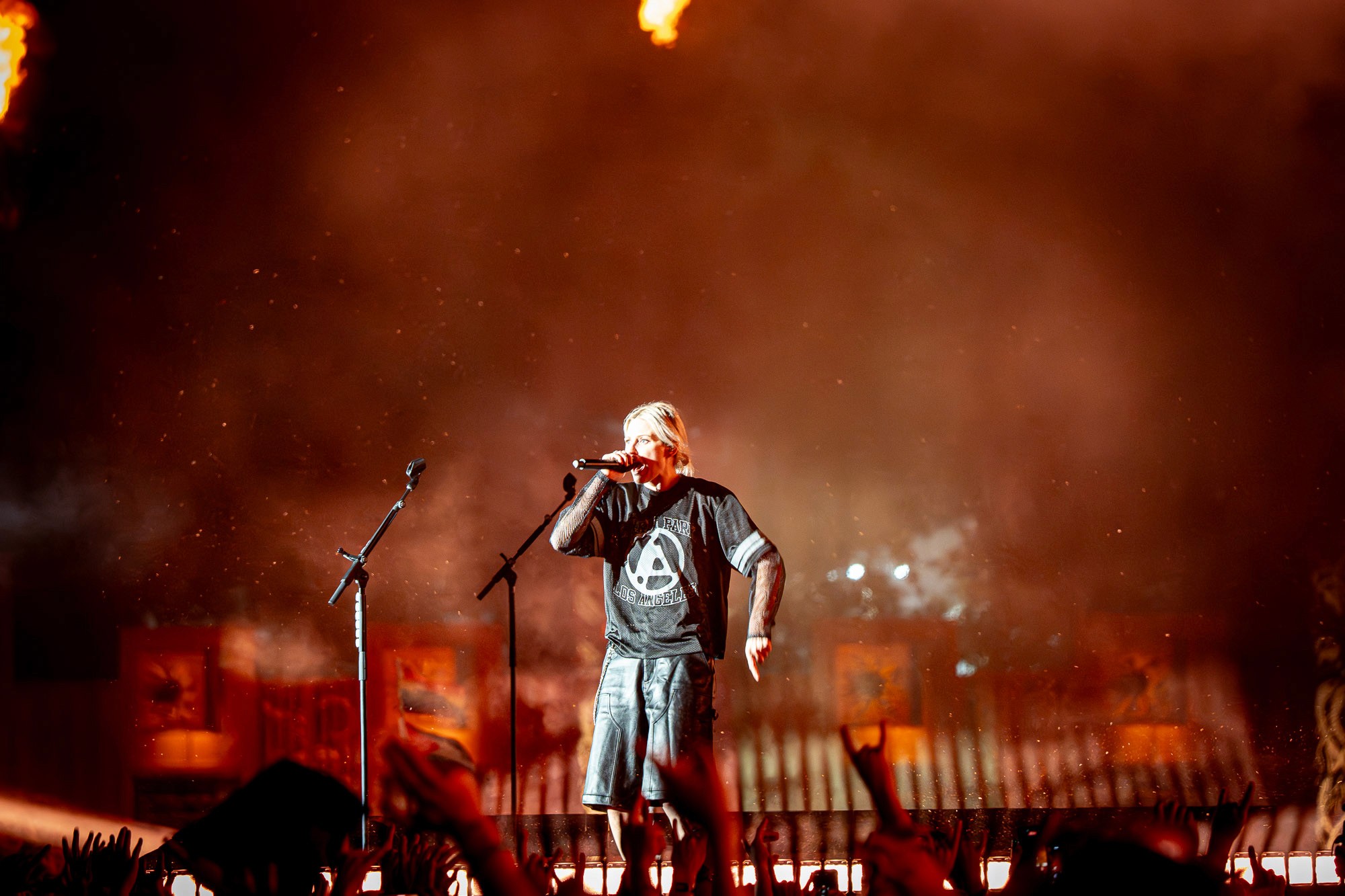 Chanteur au micro dans une brume orangée, ambiance de fin de concert nocturne