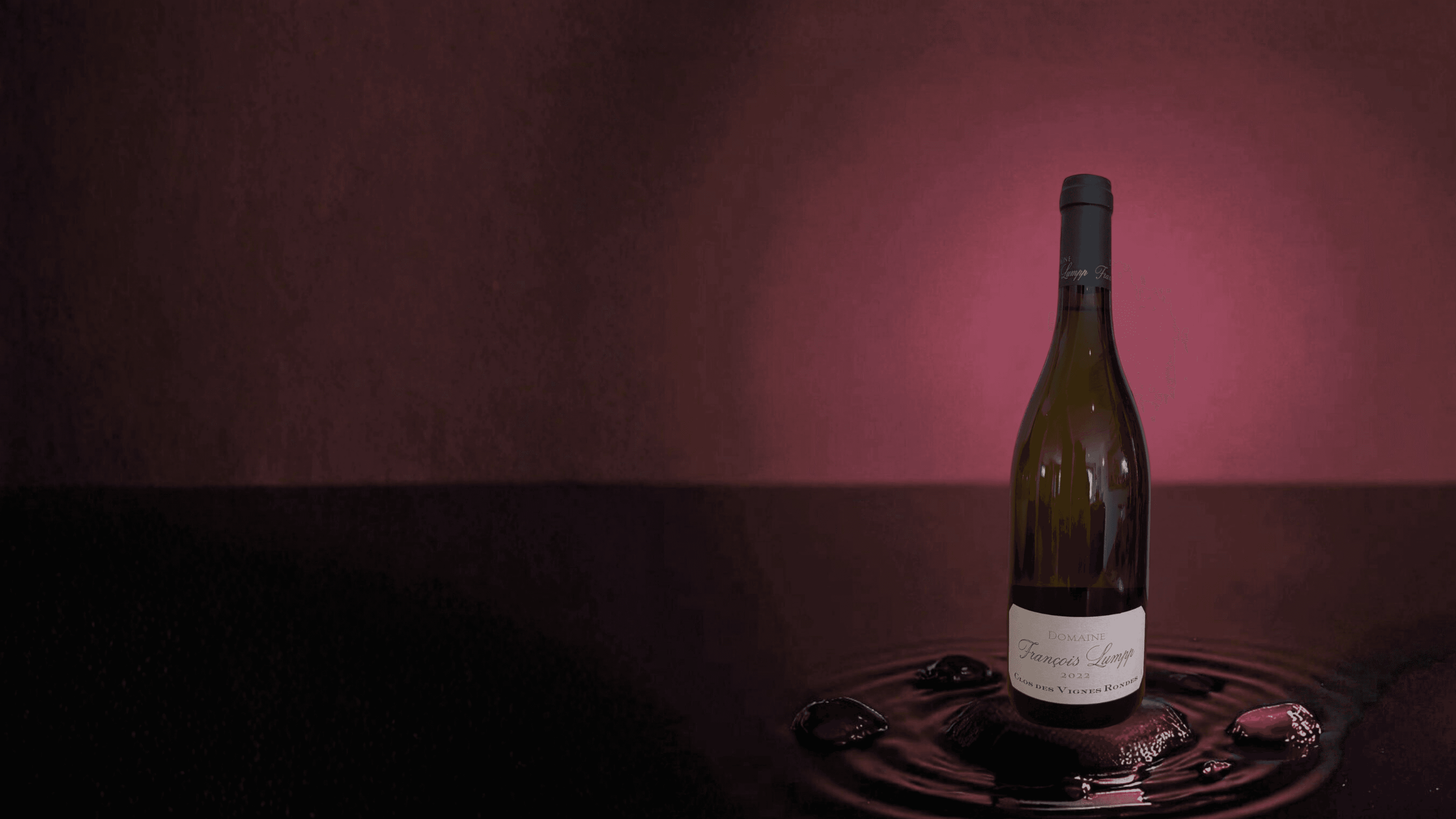 Photo de la bouteille "Clos des Vignes Rondes" du domaine François Lumpp sur fond rouge bordeaux