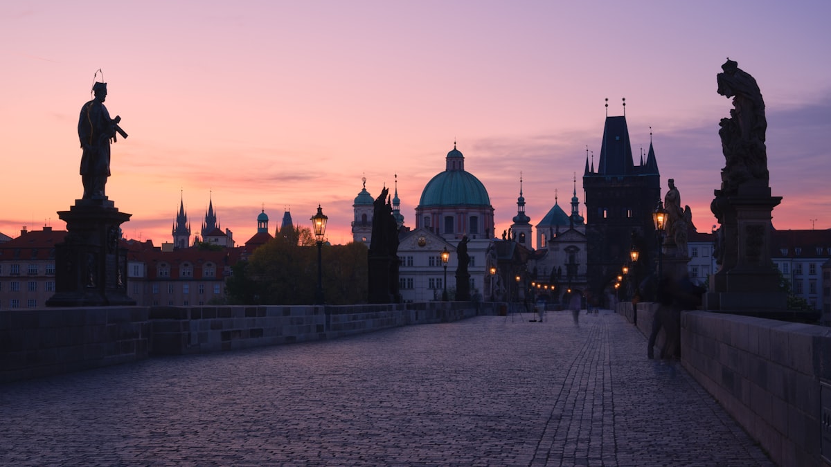 Prague's Charles Bridge at dawn with baroque statues and the castle beyond