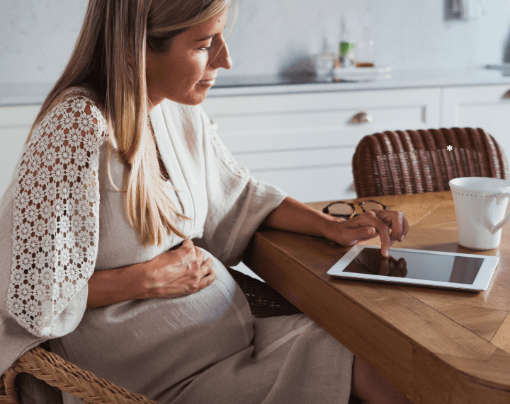 Pregnant woman using a tablet at home to read information about The Parenting Path programme.