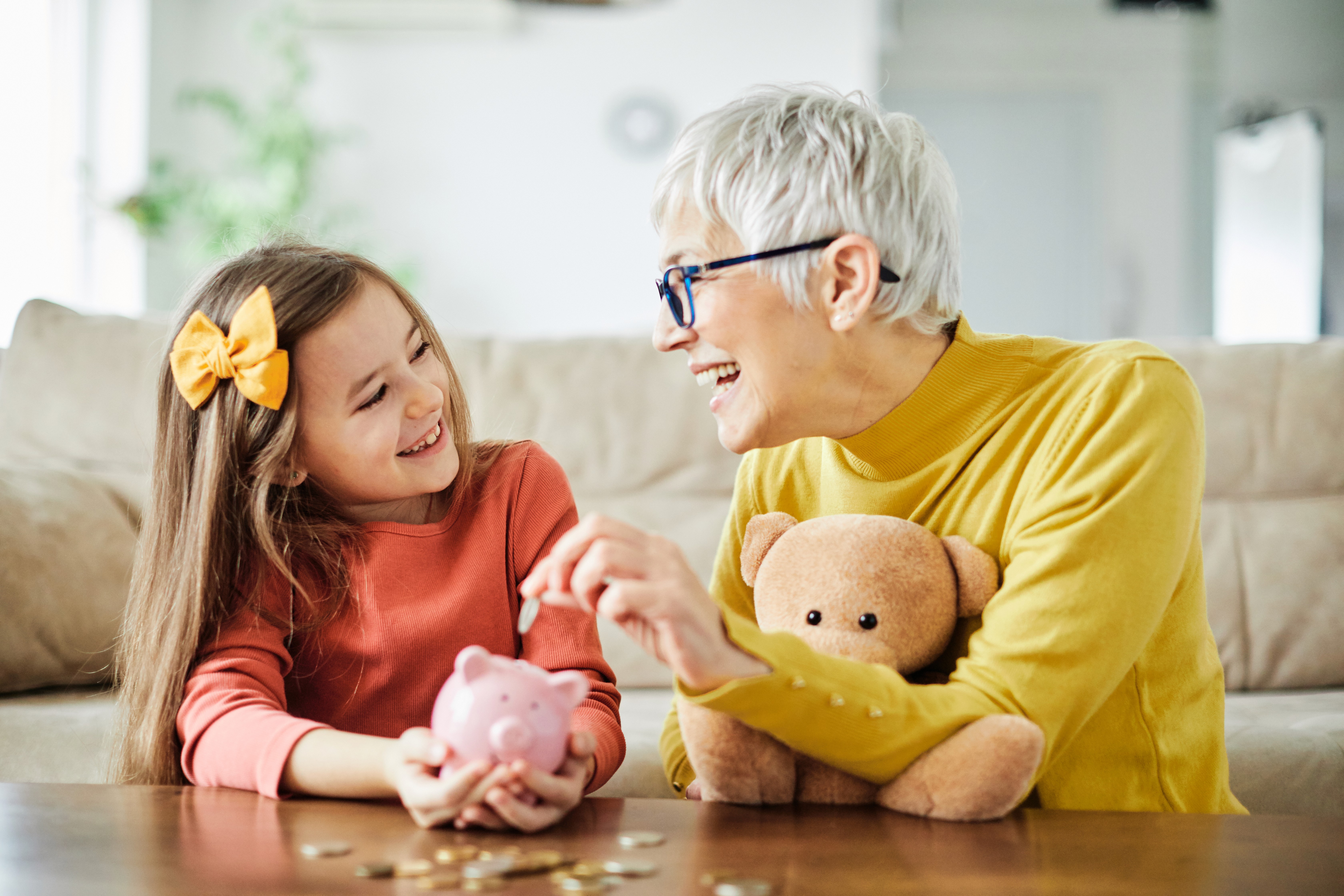 Großmutter und Kind sparen gemeinsam Geld im Sparschwein und lernen früh den bewussten Umgang mit Geld