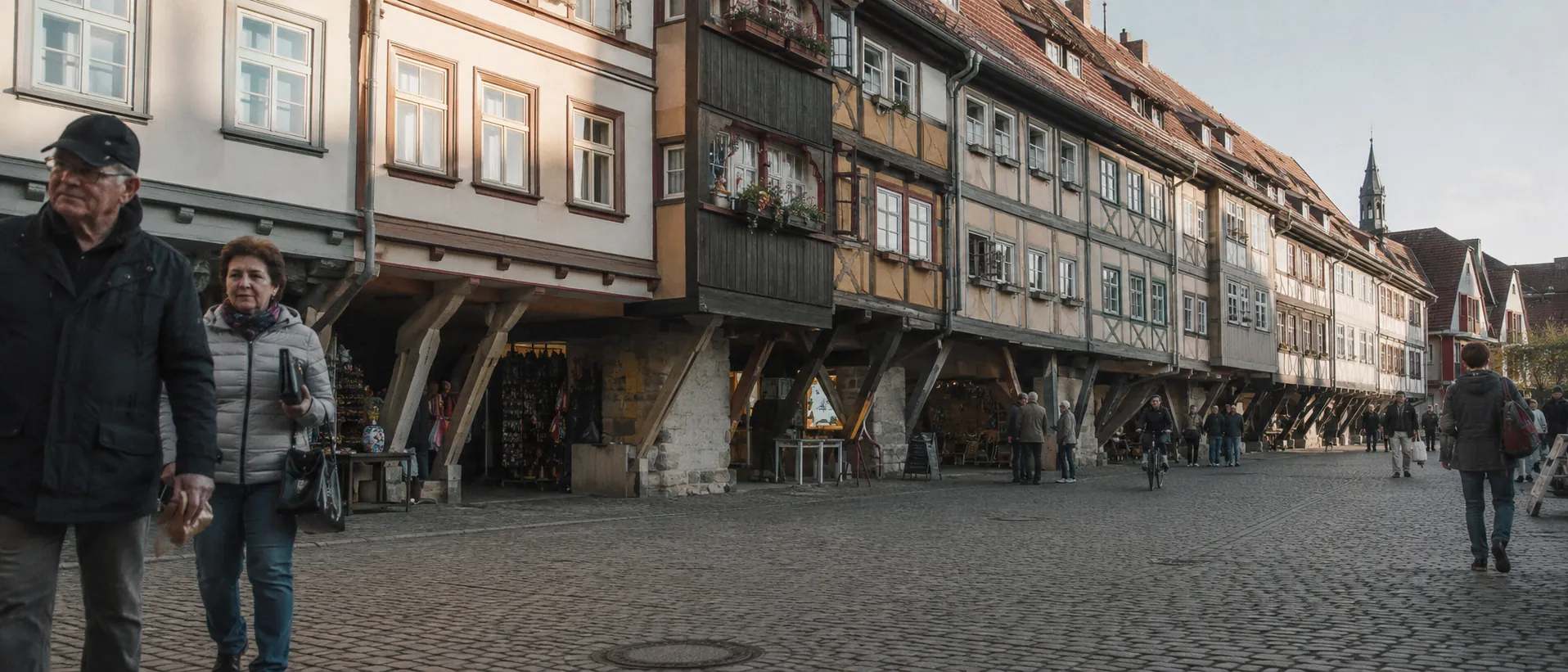 Erfurter Krämerbrücke mit Kopfsteinpflaster, Geschäften und Passanten im Morgenlicht