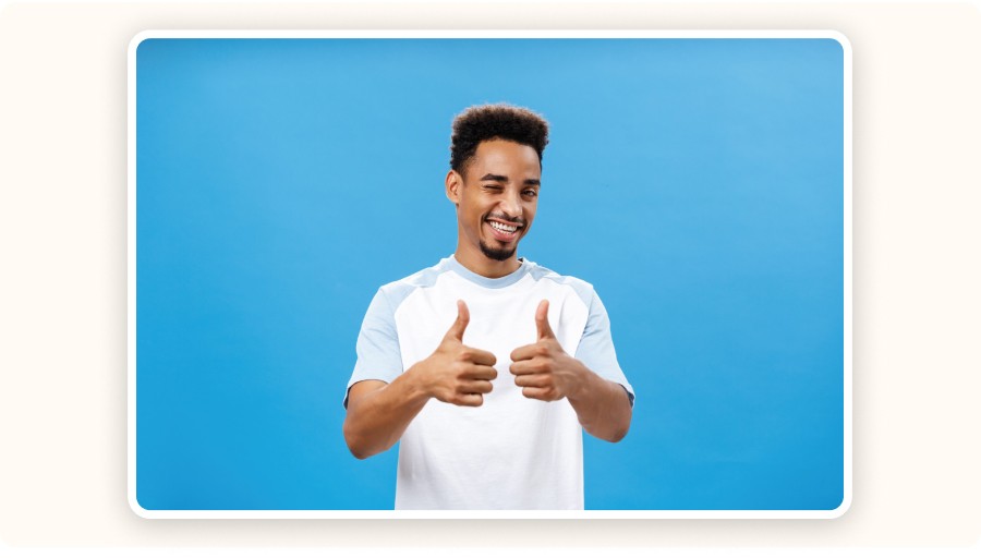 Smiling man giving thumbs up gesture against blue background