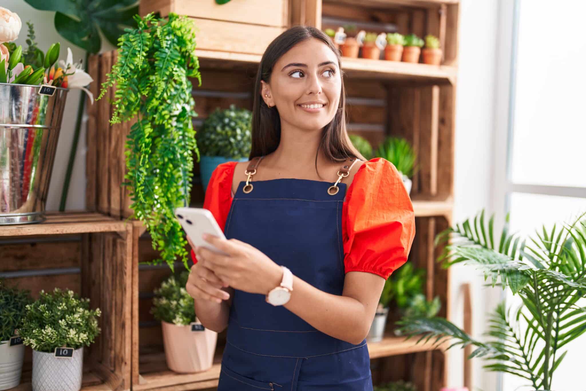 Entrepreneuse dans une boutique de plantes, symbolisant la stabilité et la sécurité offertes par une assurance vie permanente payable en 20 ans.