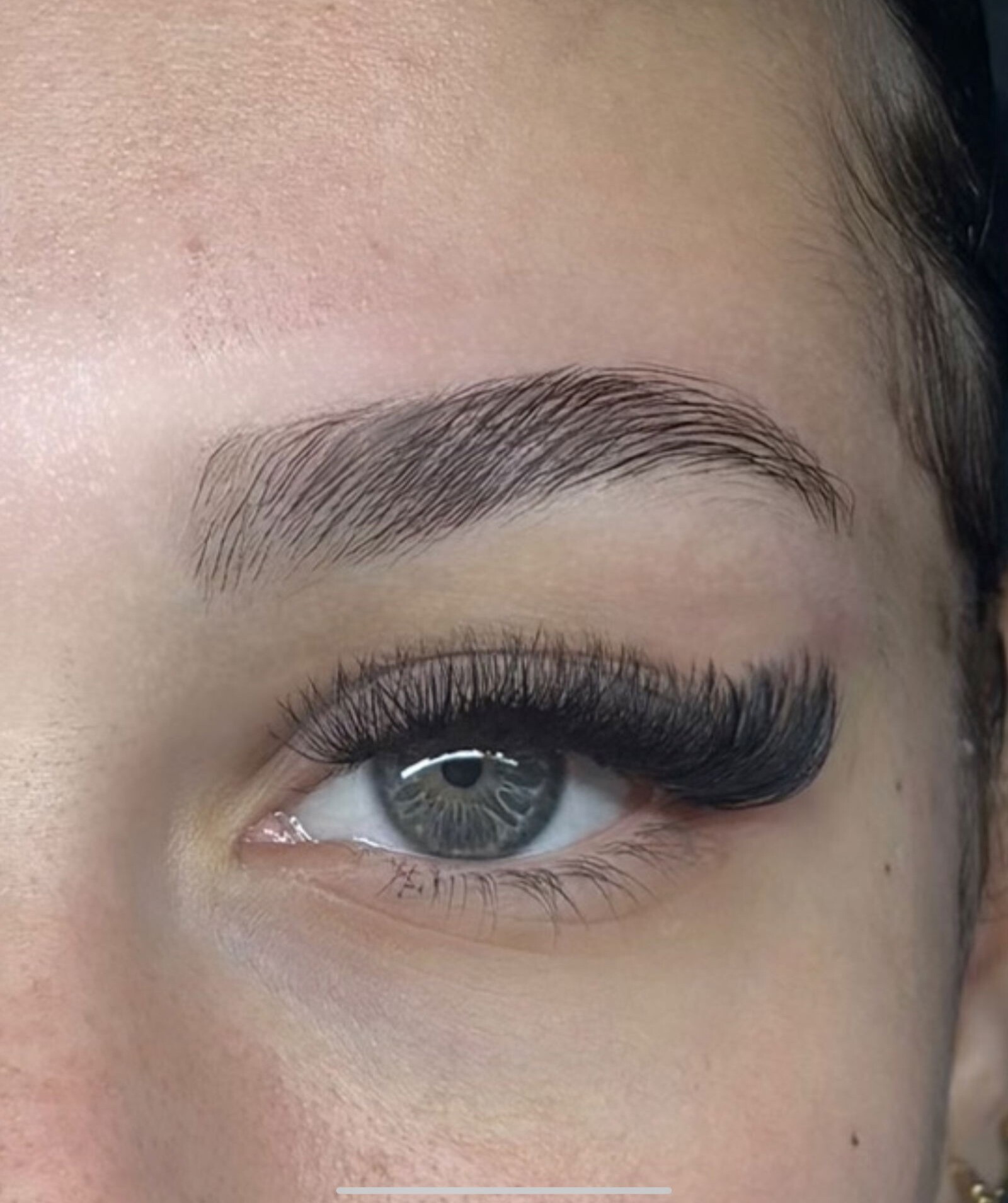 Extension de cils volume sur œil gris-bleu – cils recourbés et denses, pose professionnelle en institut spécialisé dans la beauté du regard.