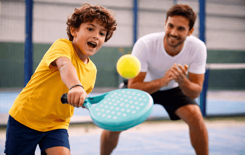 Kid playing padel with coach