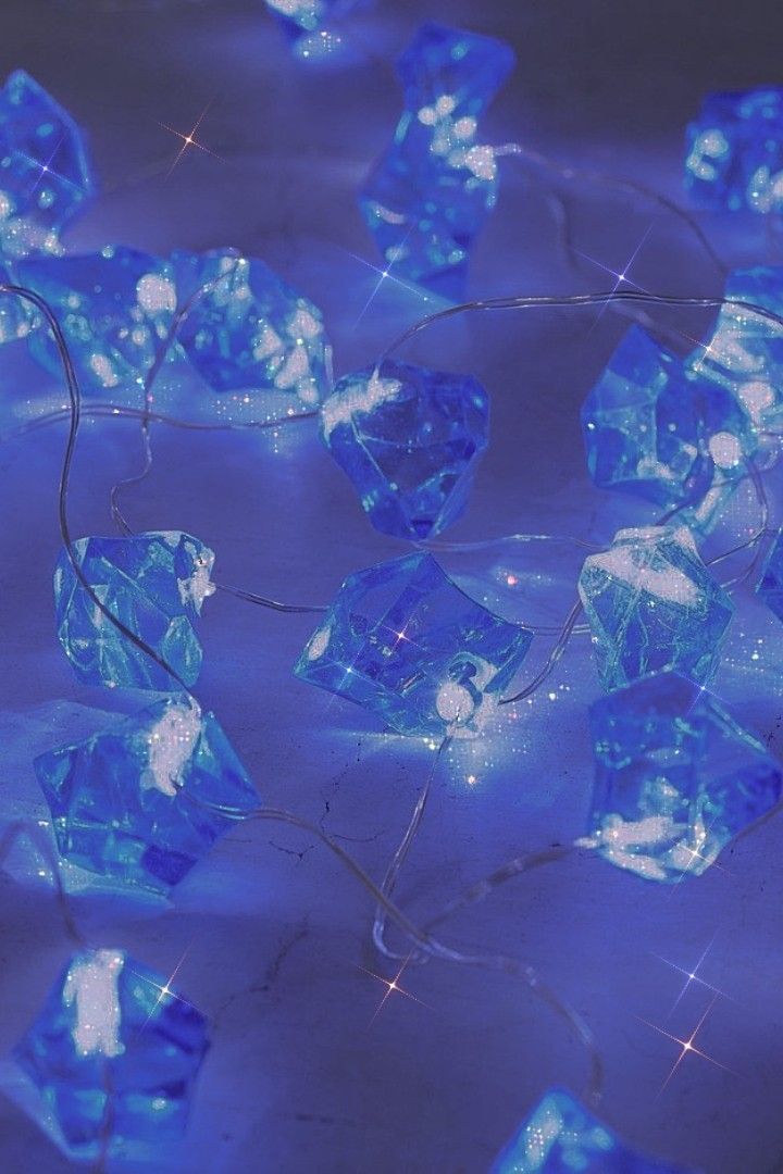 A close-up of a hand wearing multiple decorative rings against a blue background.